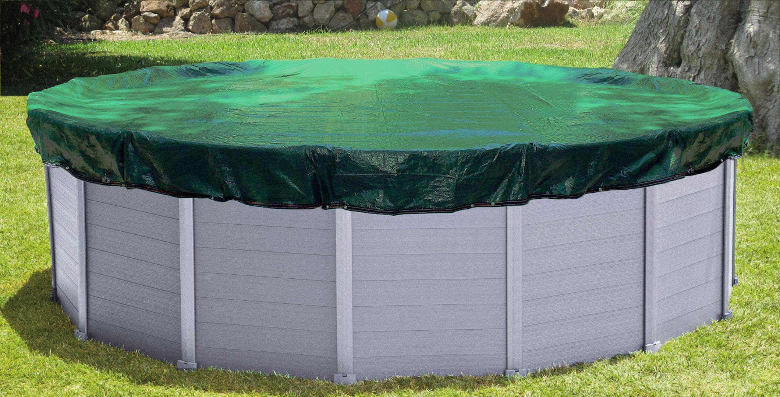 Une piscine hors-sol ronde avec des murs gris sur l'herbe, couverte par une bâche verte.