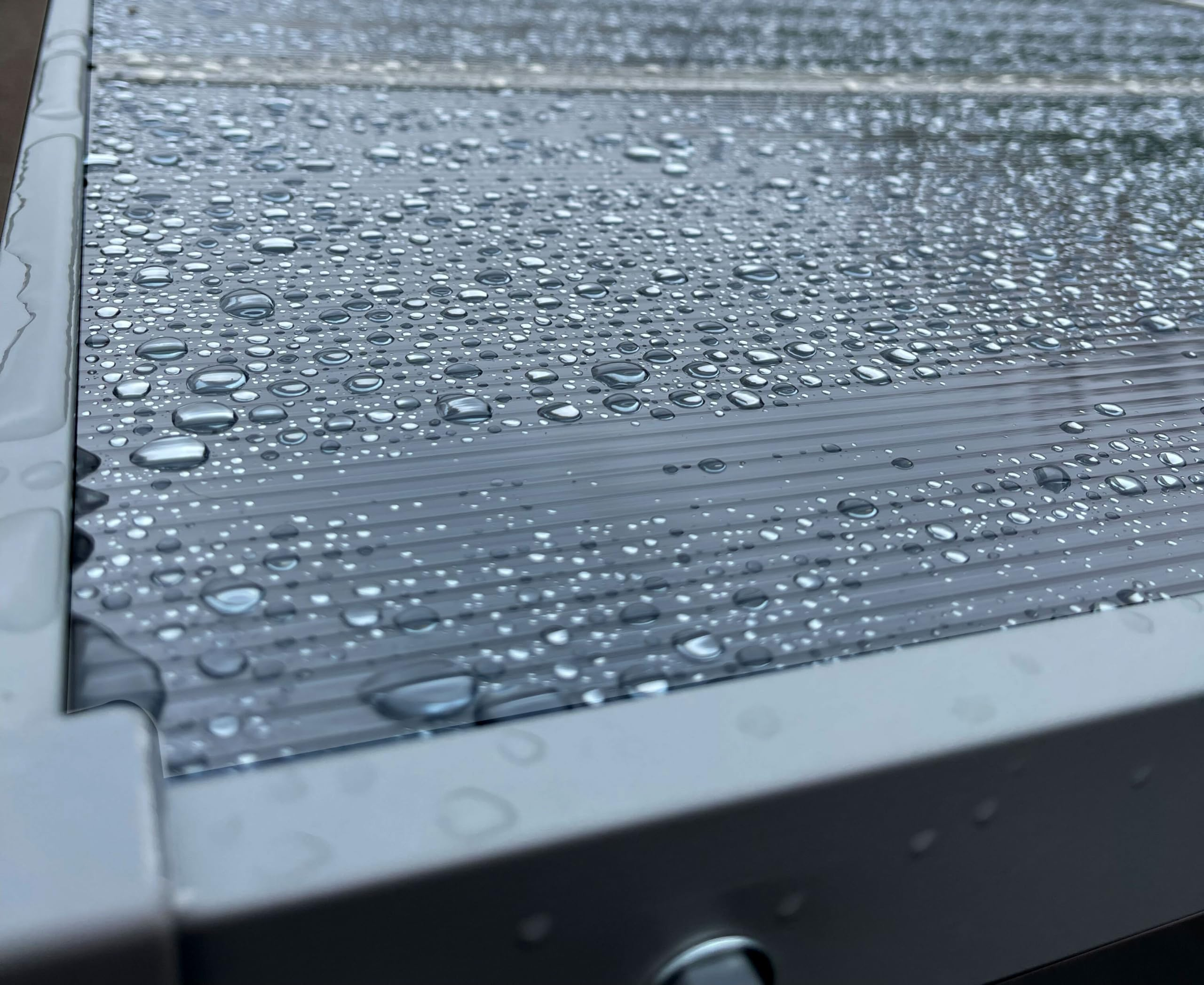 Gouttes d'eau sur une surface en plastique gris avec un cadre métallique.