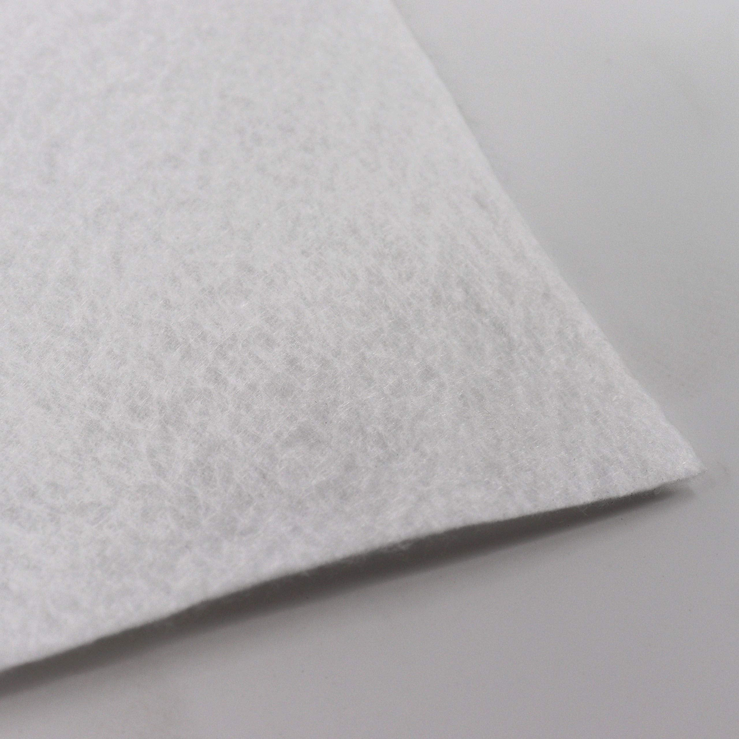 Gros plan sur un matériau non tissé blanc et fibreux sur une surface claire.