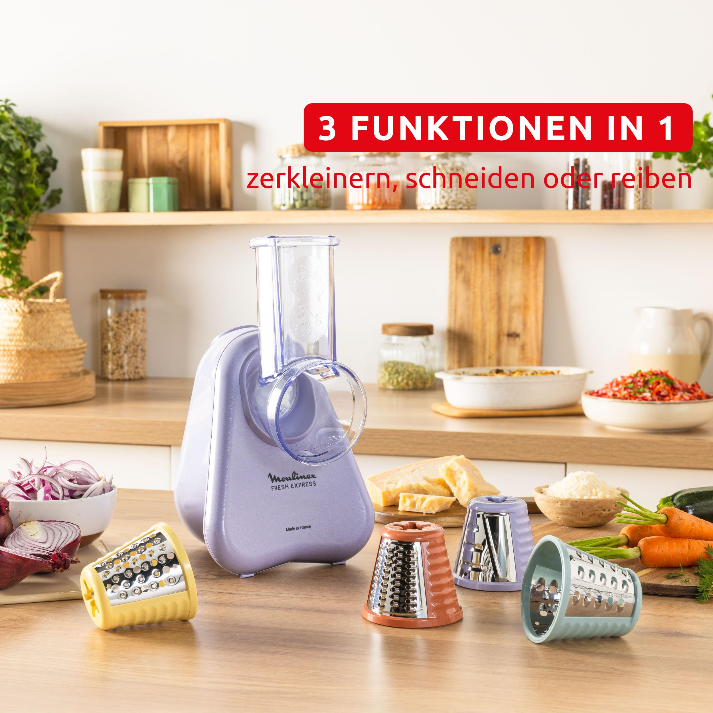 Grattugia Moulinex viola con quattro accessori colorati e verdure preparate in una cucina moderna.