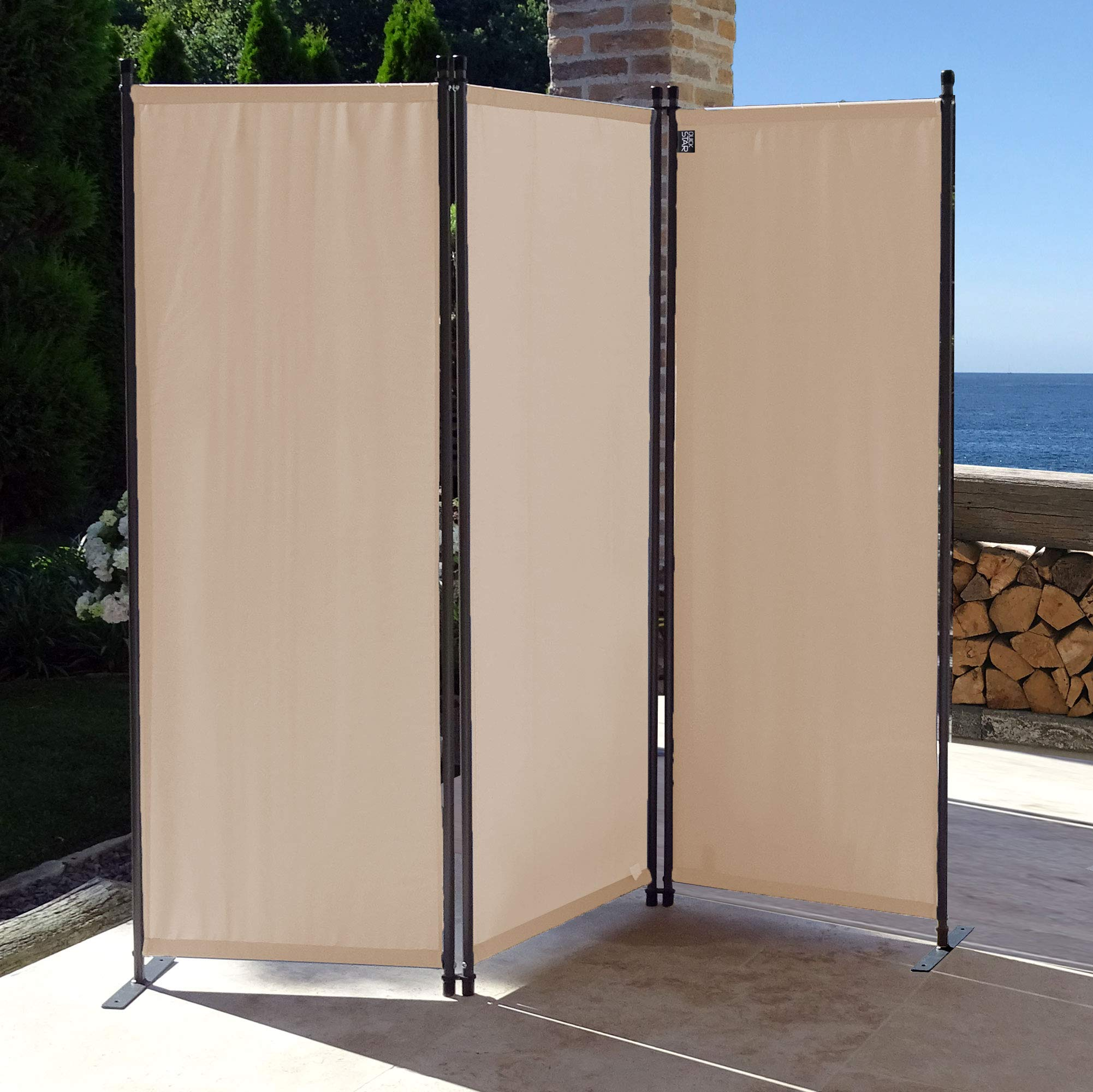Ein dreiteiliger, beige Raumteiler auf einer Terrasse mit Meerblick im Hintergrund.