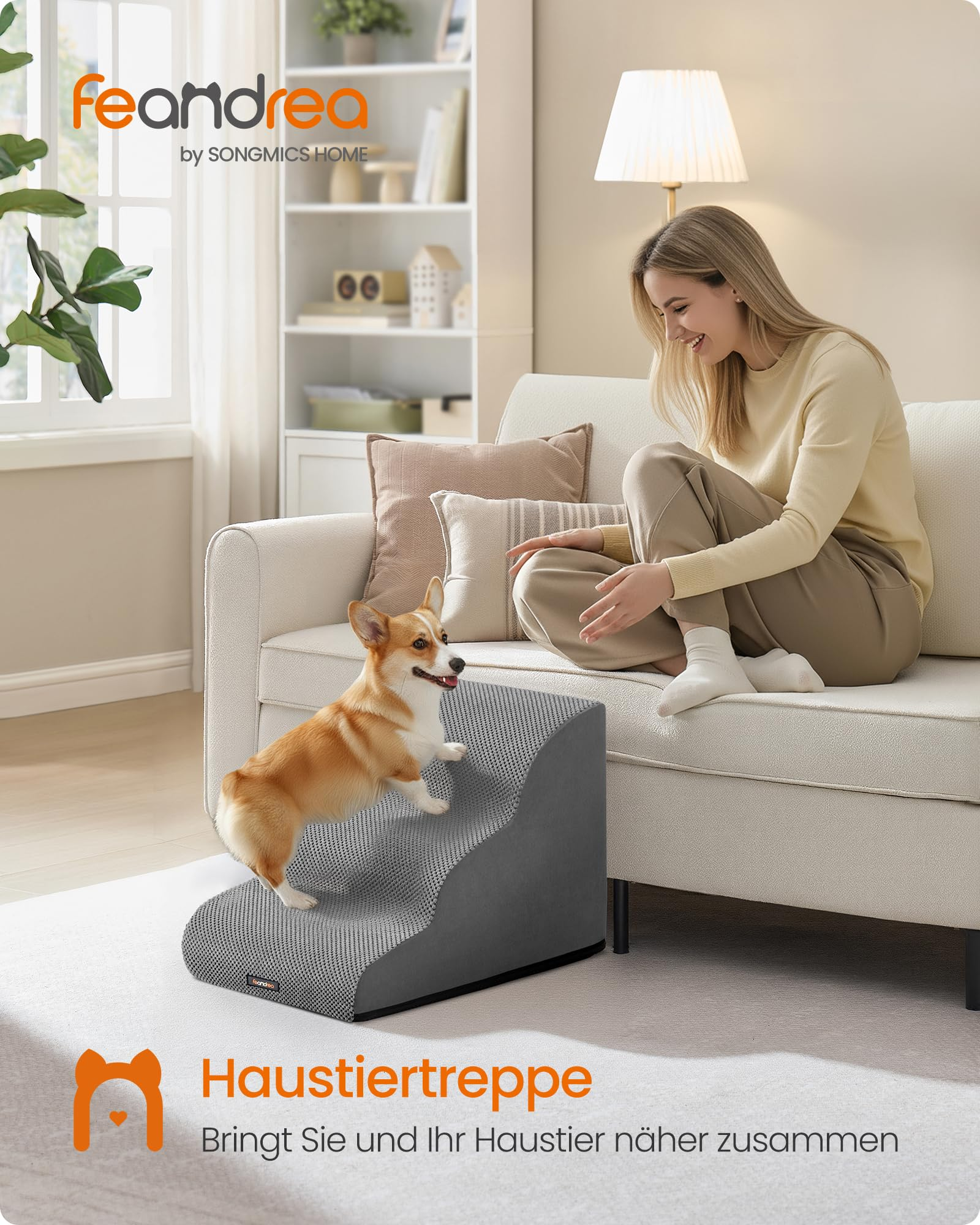 Une femme est assise sur un canapé tandis qu'un chien Corgi monte un escalier gris pour animaux.