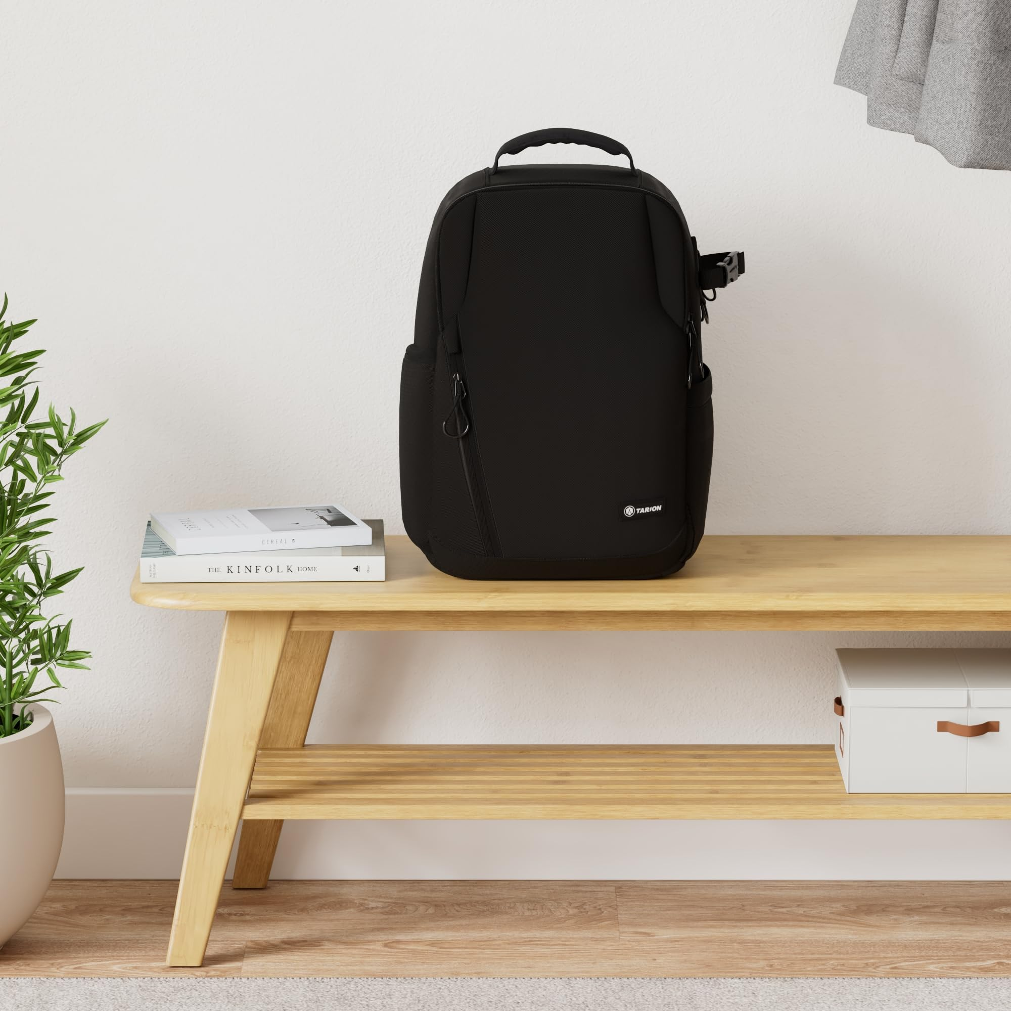 Ein schwarzer Rucksack steht auf einer Holzbank neben zwei Büchern.