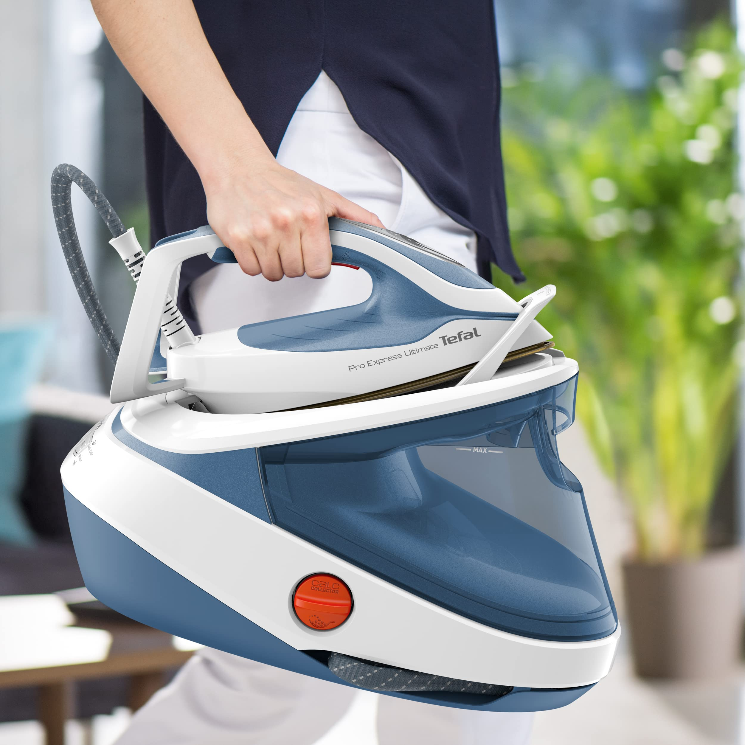 Eine Person trägt ein blau-weißes Tefal Dampfbügeleisen in einem hellen Raum.