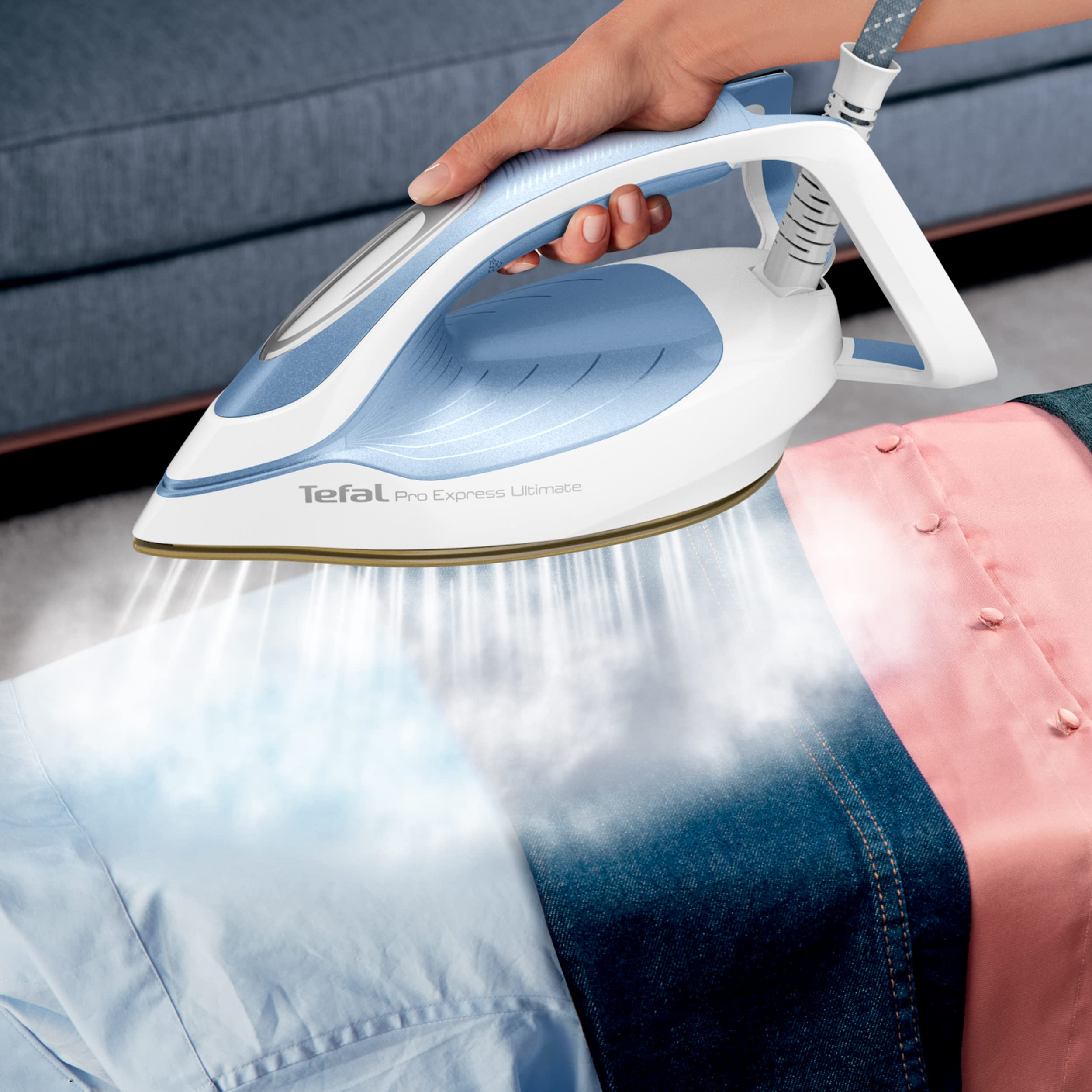 Eine Hand hält ein blau-weißes Tefal-Dampfbügeleisen, das Dampf auf Kleidung abgibt.