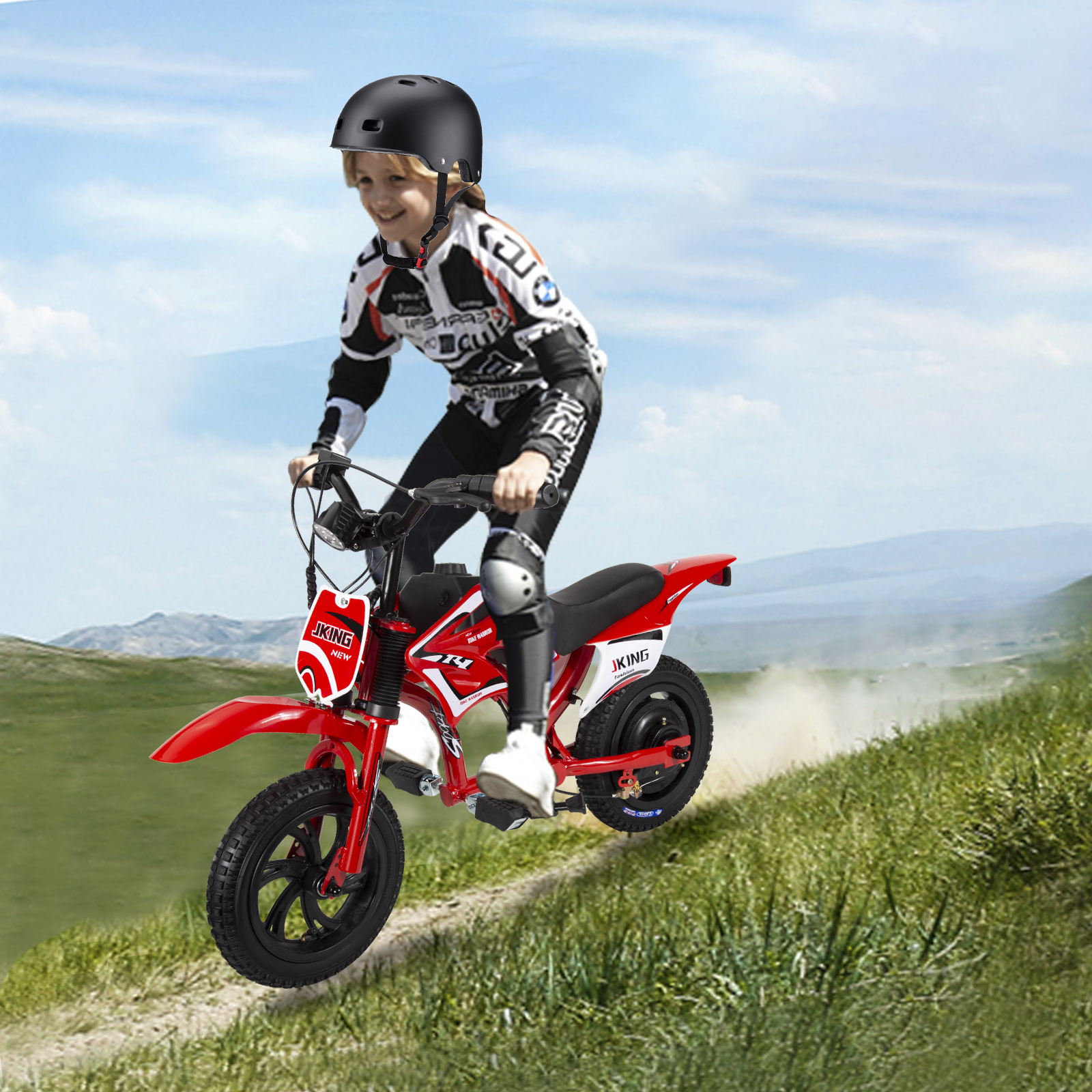 Un bambino con casco guida una mini moto rossa su una collina erbosa.