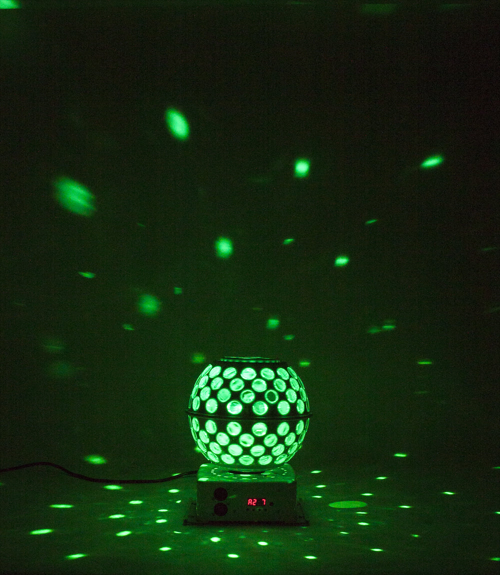 Eine grüne Diskokugel auf einer Basis projiziert grüne Lichter an die schwarze Wand.