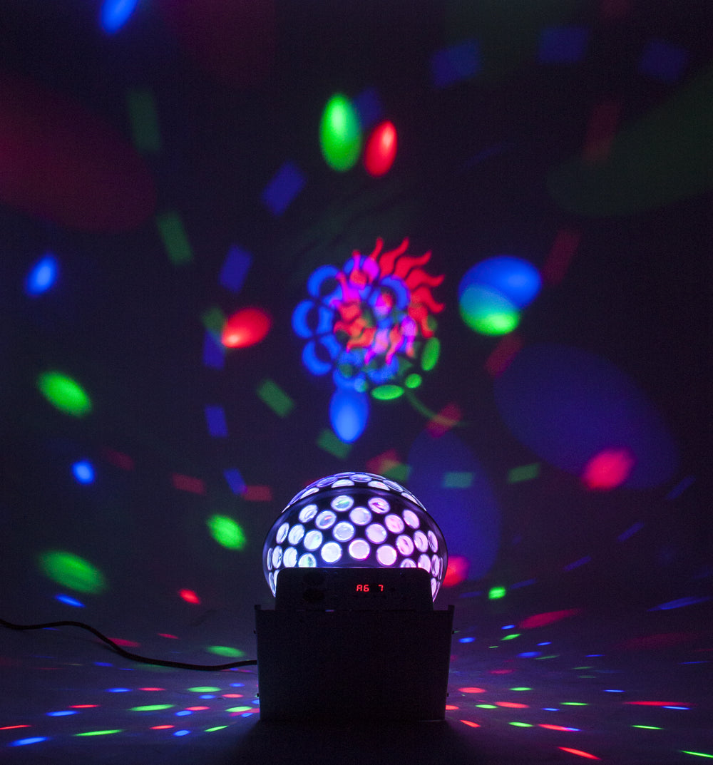 Eine Diskokugel steht auf einem Tisch und projiziert bunte Lichter an die Wand und den Boden.