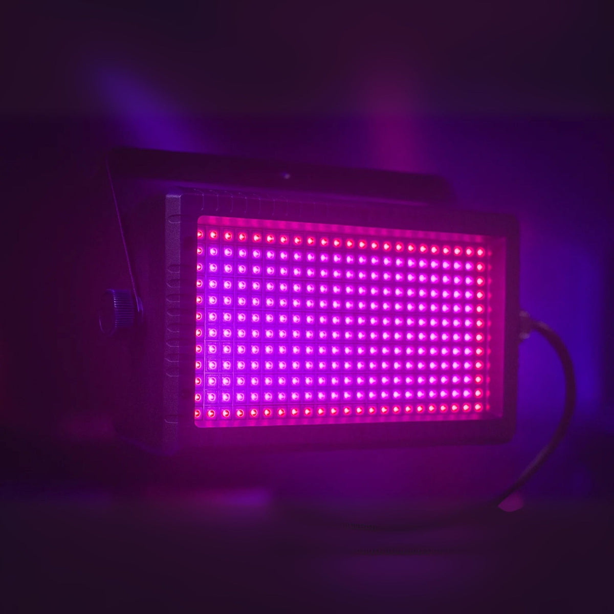 Ein rechteckiges LED-Panel leuchtet in leuchtendem Pink und Lila in einem dunklen Raum.