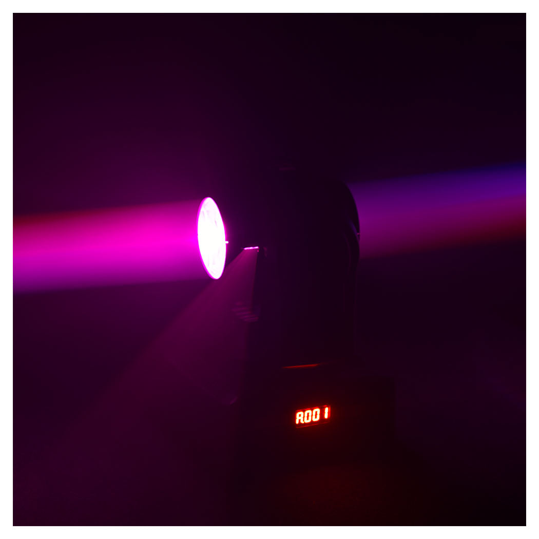 Ein schwarzer Bühnenscheinwerfer wirft in einem dunklen Raum einen leuchtend rosa Strahl, Basis mit roter Digitalanzeige.