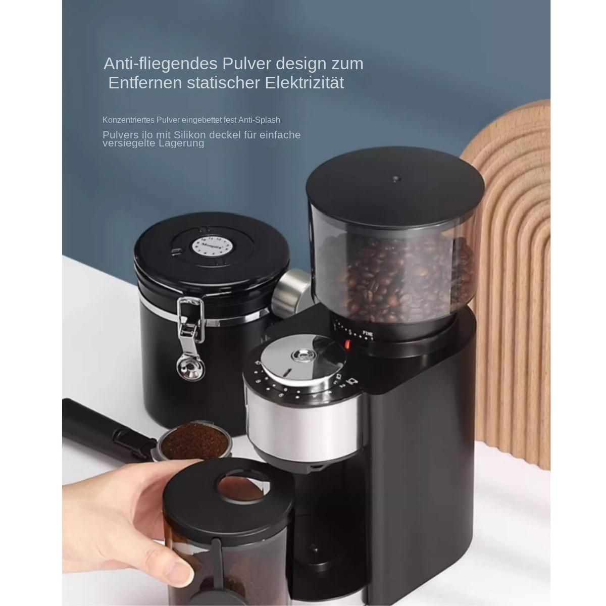 Eine schwarze Kaffeemühle mit Kaffeebohnen und ein Behälter stehen auf einer weißen Oberfläche mit deutschem Text.