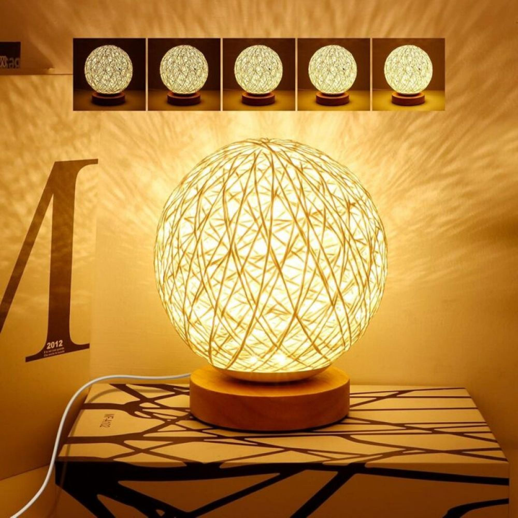 Eine runde Rattanlampe auf einem Holzsockel mit warmem Licht strahlt gegen eine beige Wand.