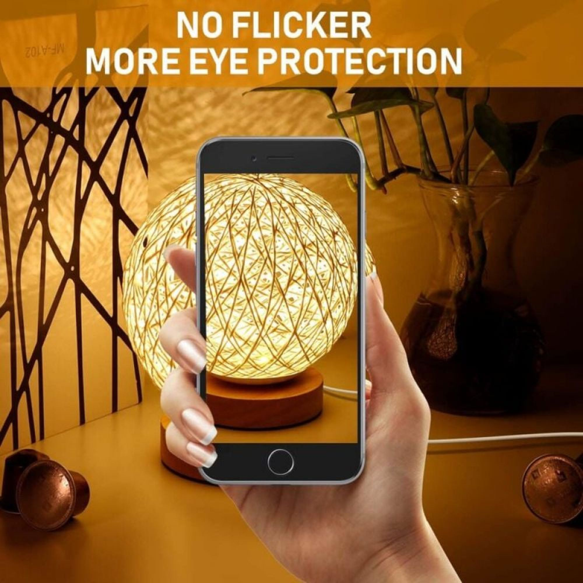 Hand hält Smartphone, das eine beleuchtete Kugellampe fotografiert, neben Pflanze und abstrakter Deko.