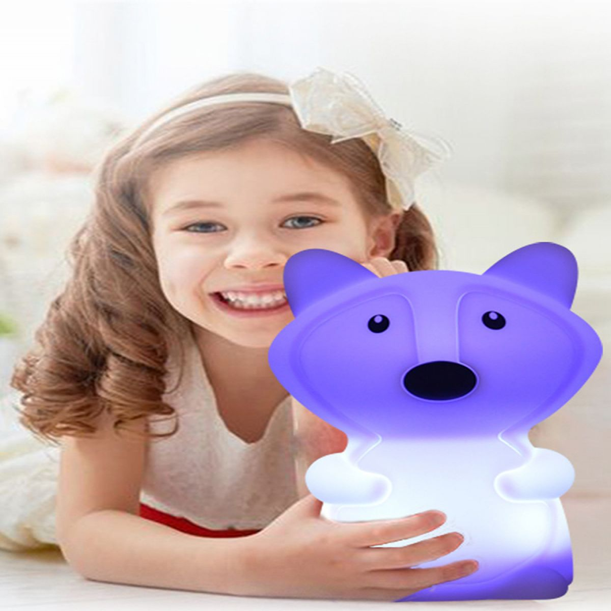 Ein glückliches Mädchen liegt und hält eine leuchtende, violette Bärenlampe.