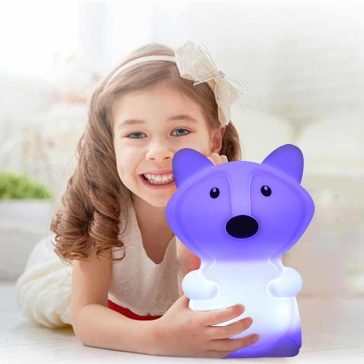 Ein kleines Mädchen lächelt und hält eine violette, leuchtende Tierlampe in den Händen.