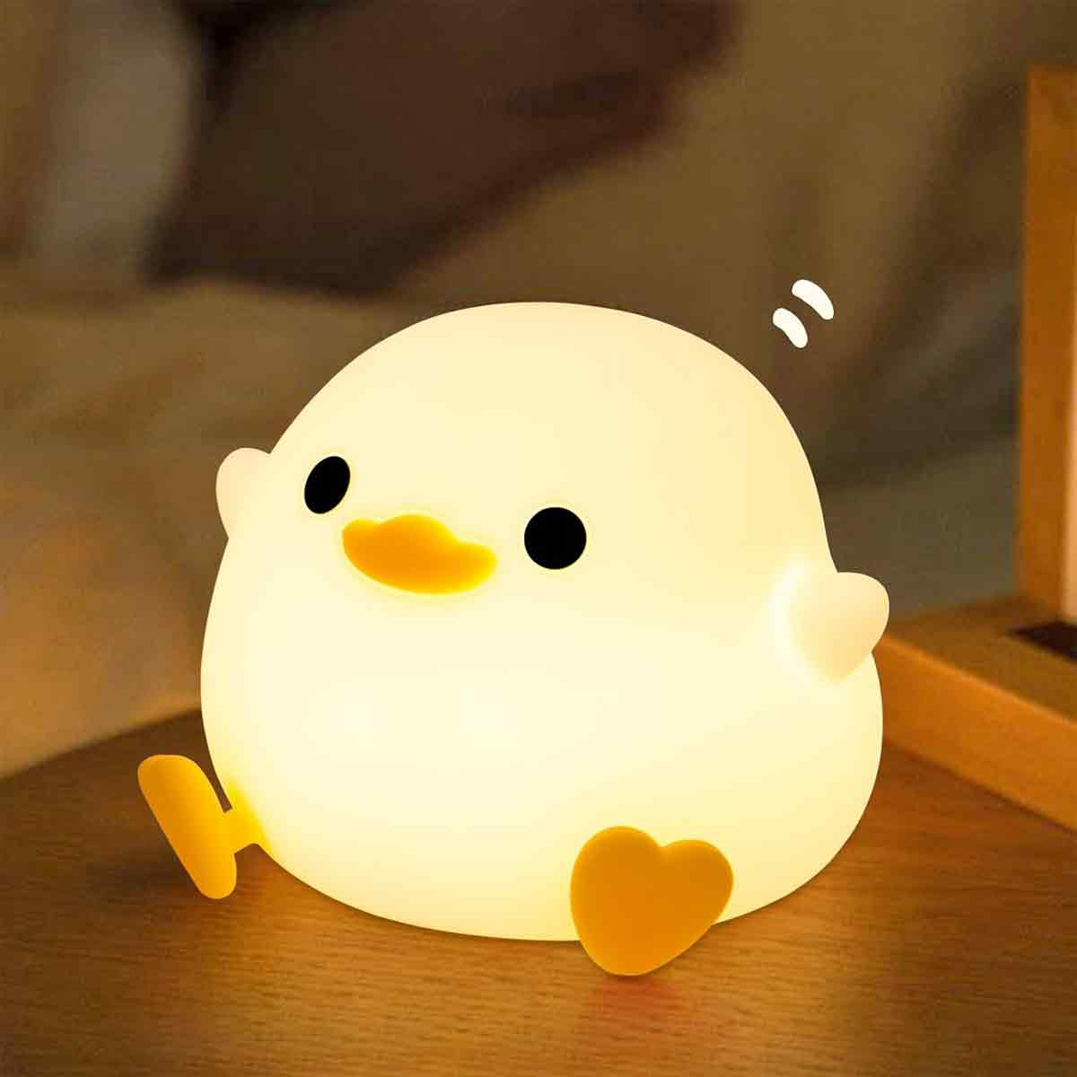 Ein süßes, leuchtendes Enten-Nachtlicht steht auf einer Holzoberfläche in einem gedimmten Raum.