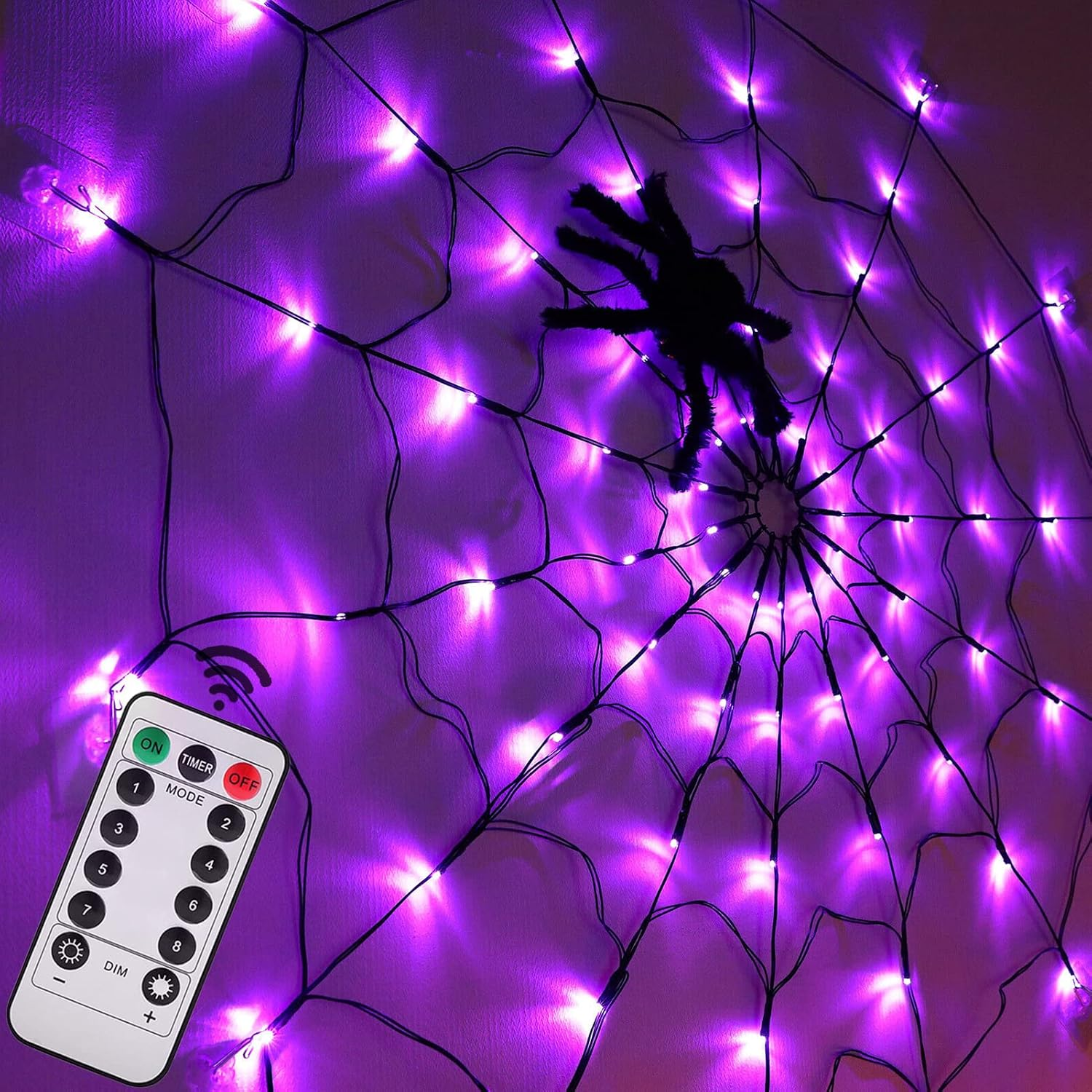 Violette Spinnennetz-Lichterkette an einer Wand mit großer schwarzer Spinne und weißer Fernbedienung.