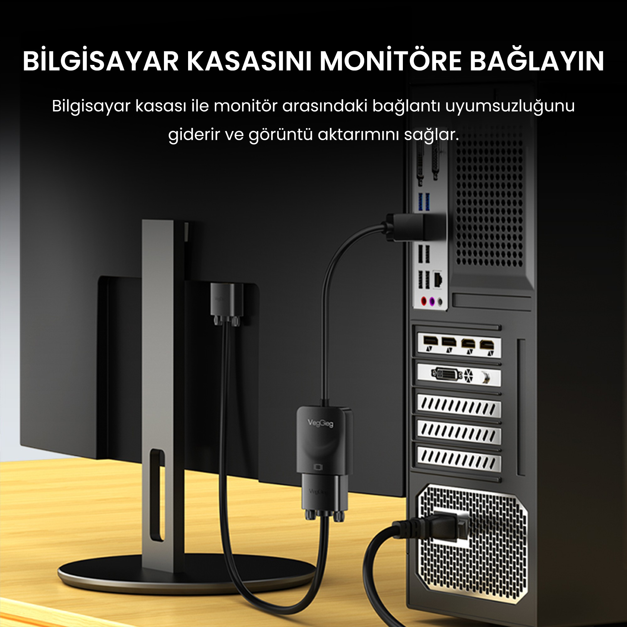 Ahşap masada bir adaptör kablosuyla monitöre bağlı siyah bilgisayar kasası.