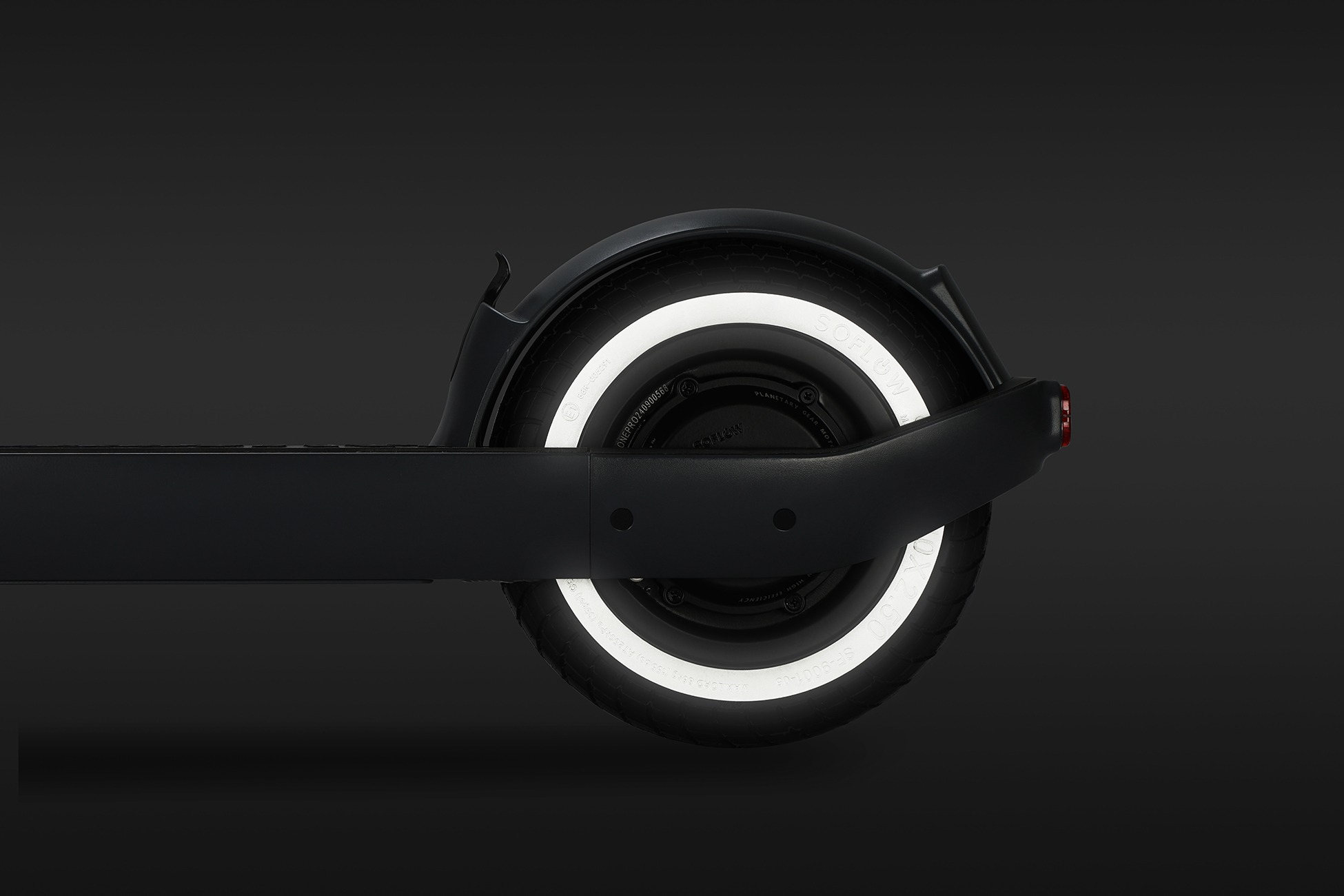 Seitenansicht des Hinterrads eines schwarzen E-Scooters mit einem auffälligen weißen Leuchtring auf dem Reifen.