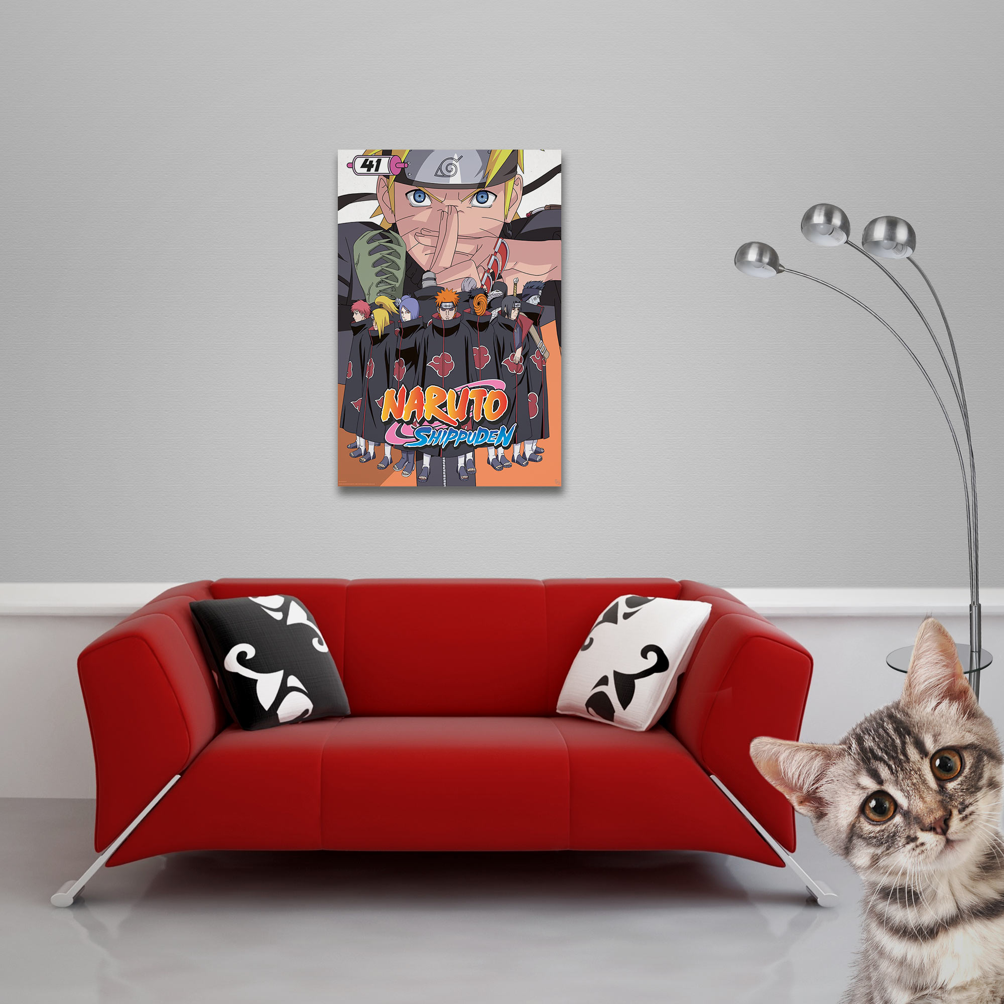 Ein rotes Sofa vor einer grauen Wand mit Naruto-Poster, Kissen, Stehlampe und einer neugierigen Katze.