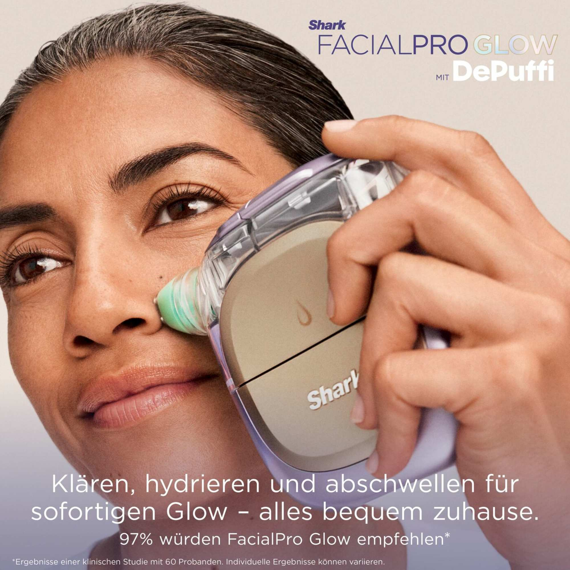Une femme tient un appareil Shark FacialPro Glow contre son visage pour nettoyer et soigner sa peau.