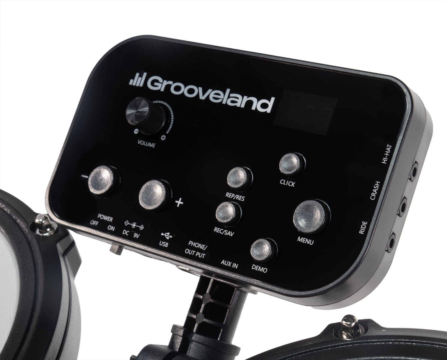 Ein schwarzes Grooveland E-Drum-Modul mit silbernen Knöpfen, Lautstärkeregler, Display und Anschlüssen auf weißem Grund.