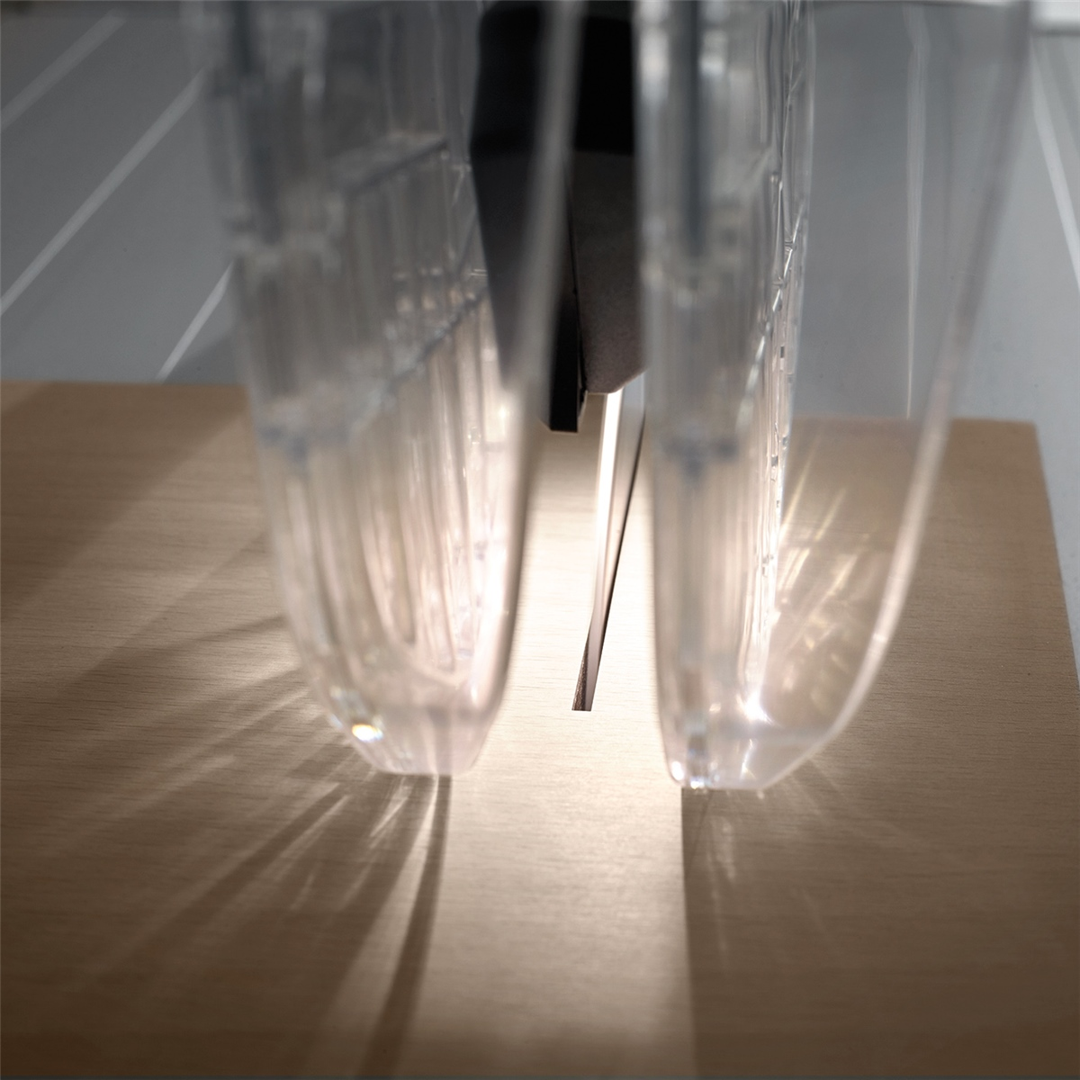 Eine helle Sägeblattspalte zwischen transparenten Schutzvorrichtungen auf einer Holzplatte.