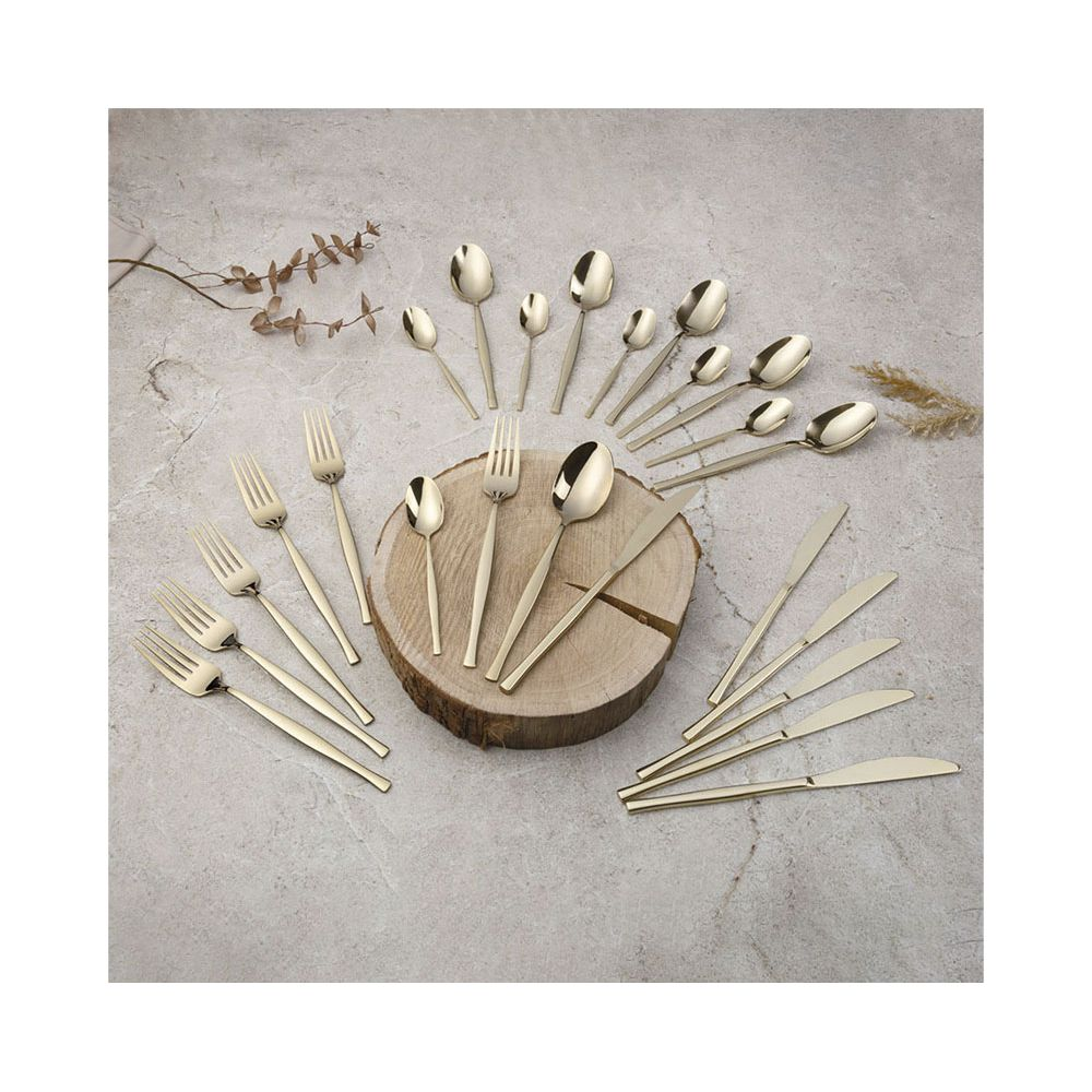 Couverts dorés comprenant fourchettes, cuillères et couteaux sur fond de pierre grise.