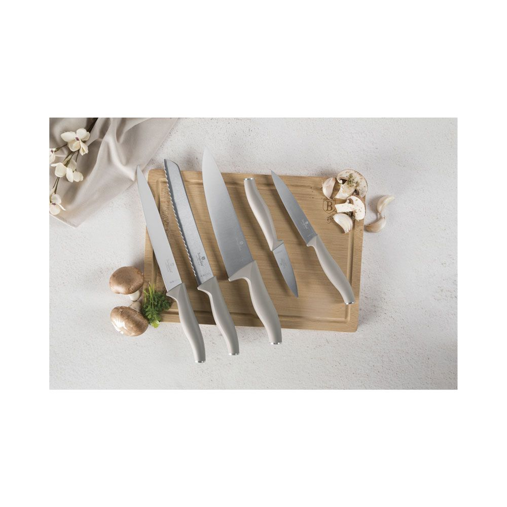 Un ensemble de cinq couteaux de cuisine à manches gris clair sur une planche à découper en bois avec des champignons.