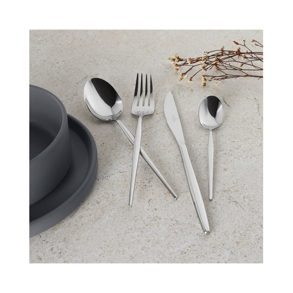 Couverts brillants avec cuillère, fourchette, couteau et petite cuillère à côté d'un bol gris sur fond beige.