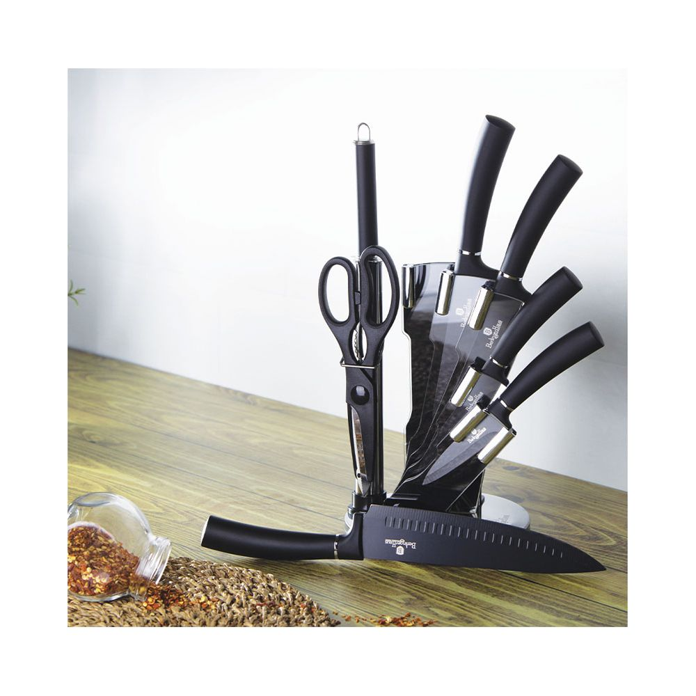 Un ensemble de couteaux noirs avec bloc, ciseaux et pot d'épices ouvert sur une table en bois.