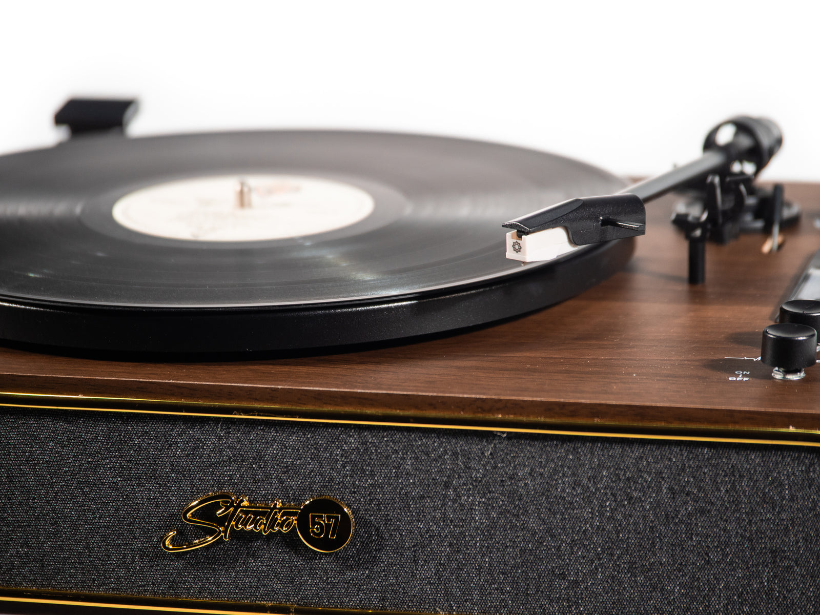 Ein hölzernen Plattenspieler mit schwarzem Vinyl und der goldenen Aufschrift Studio 57 auf der grauen Stofffront.