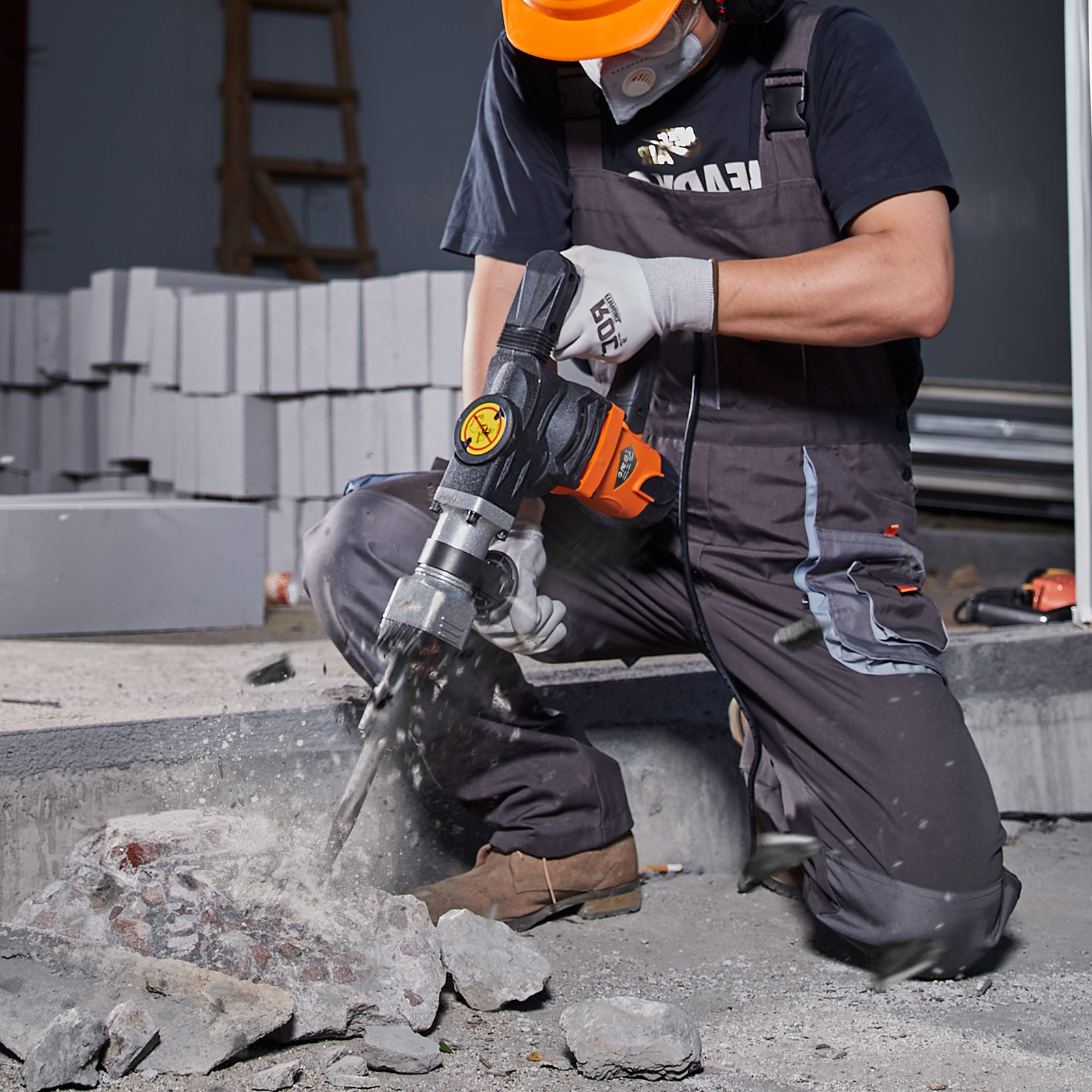 Un trabajador con casco y mascarilla usa un martillo neumático para romper hormigón.