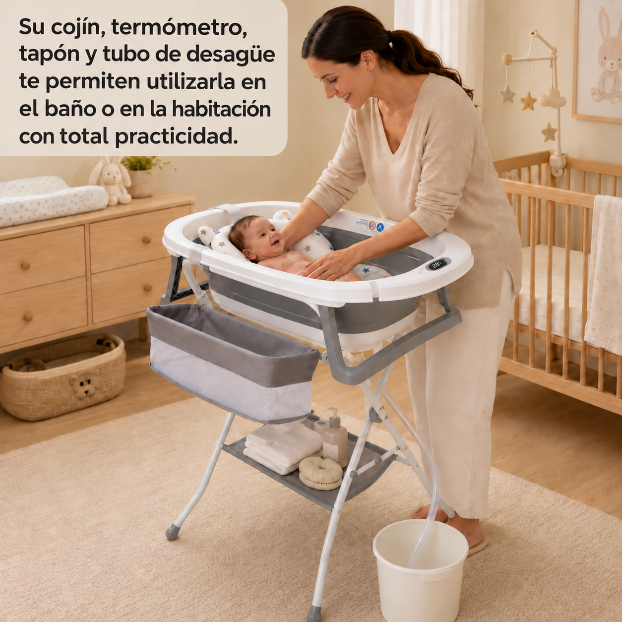 Una mujer sonriente baña a un bebé feliz en una bañera portátil gris y blanca en interior.