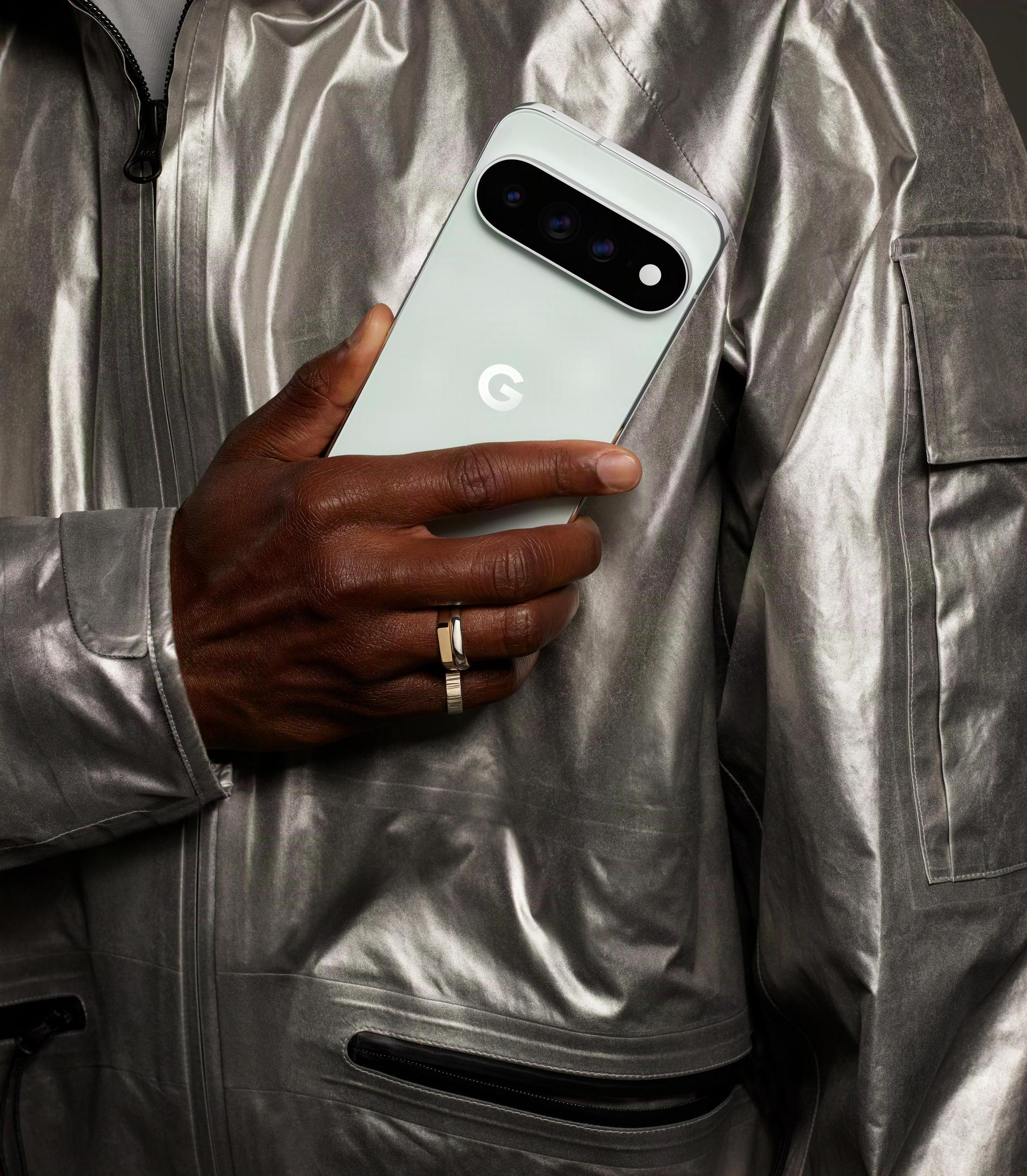 Osoba w srebrnej kurtce trzyma w ręku jasnozielony smartfon.
