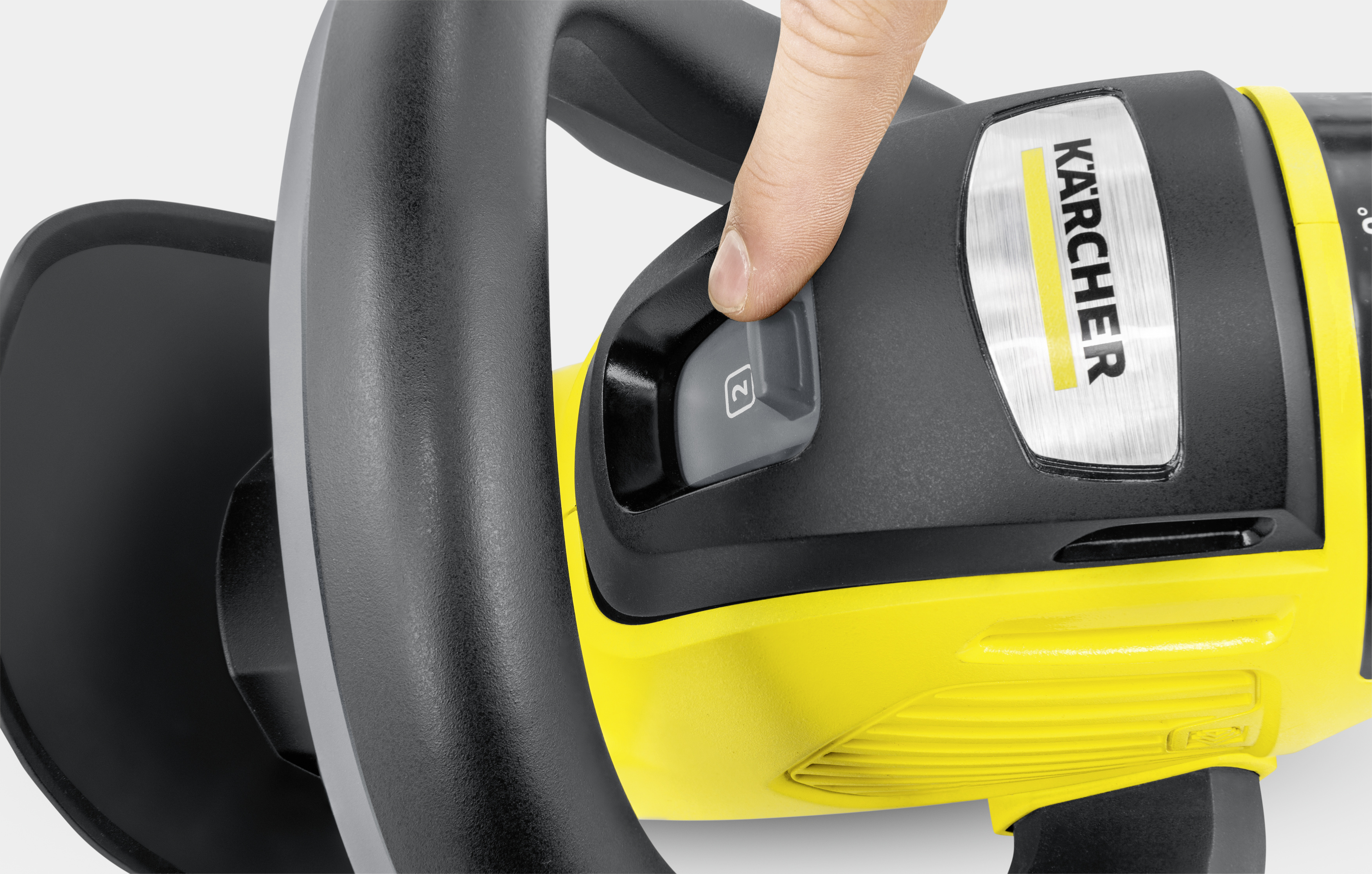 Ein Finger drückt den Startknopf einer gelb-schwarzen Kärcher-Maschine.