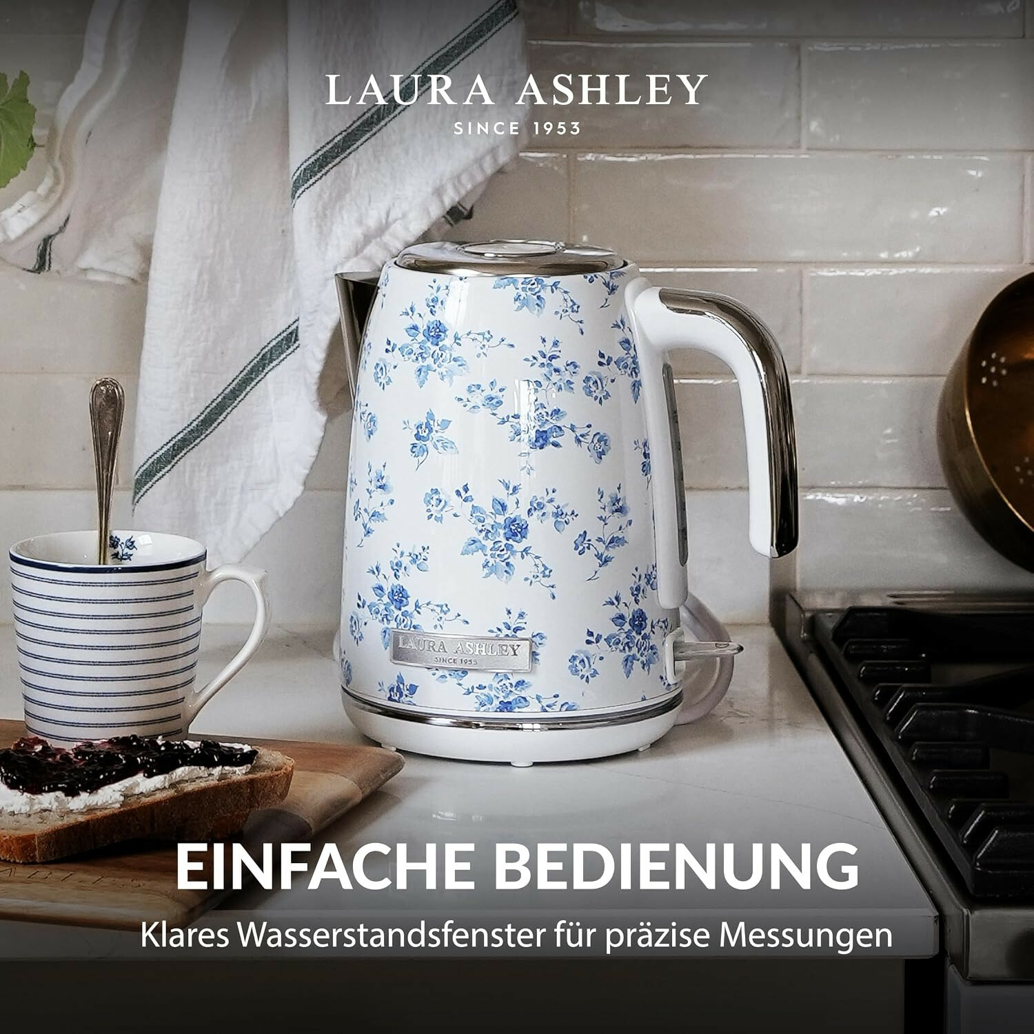 Un bollitore bianco Laura Ashley con motivo floreale blu in cucina accanto a una tazza e pane tostato.
