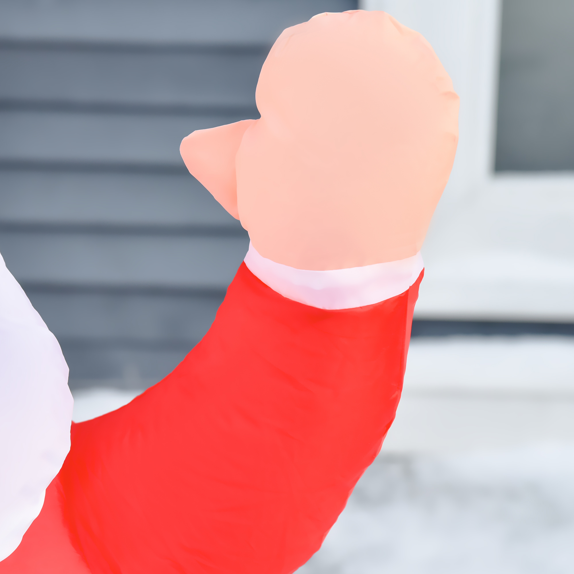 Un brazo doblado de una figura de Papá Noel con manga roja, puño blanco y un guante color carne.
