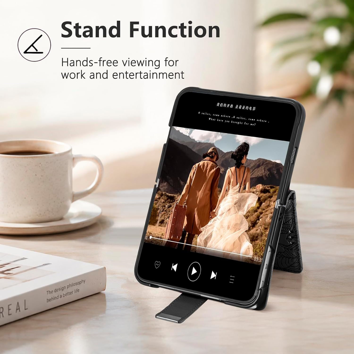 Ein Smartphone steht auf einem Tisch, zeigt ein Video und daneben stehen eine Kaffeetasse und ein Buch.