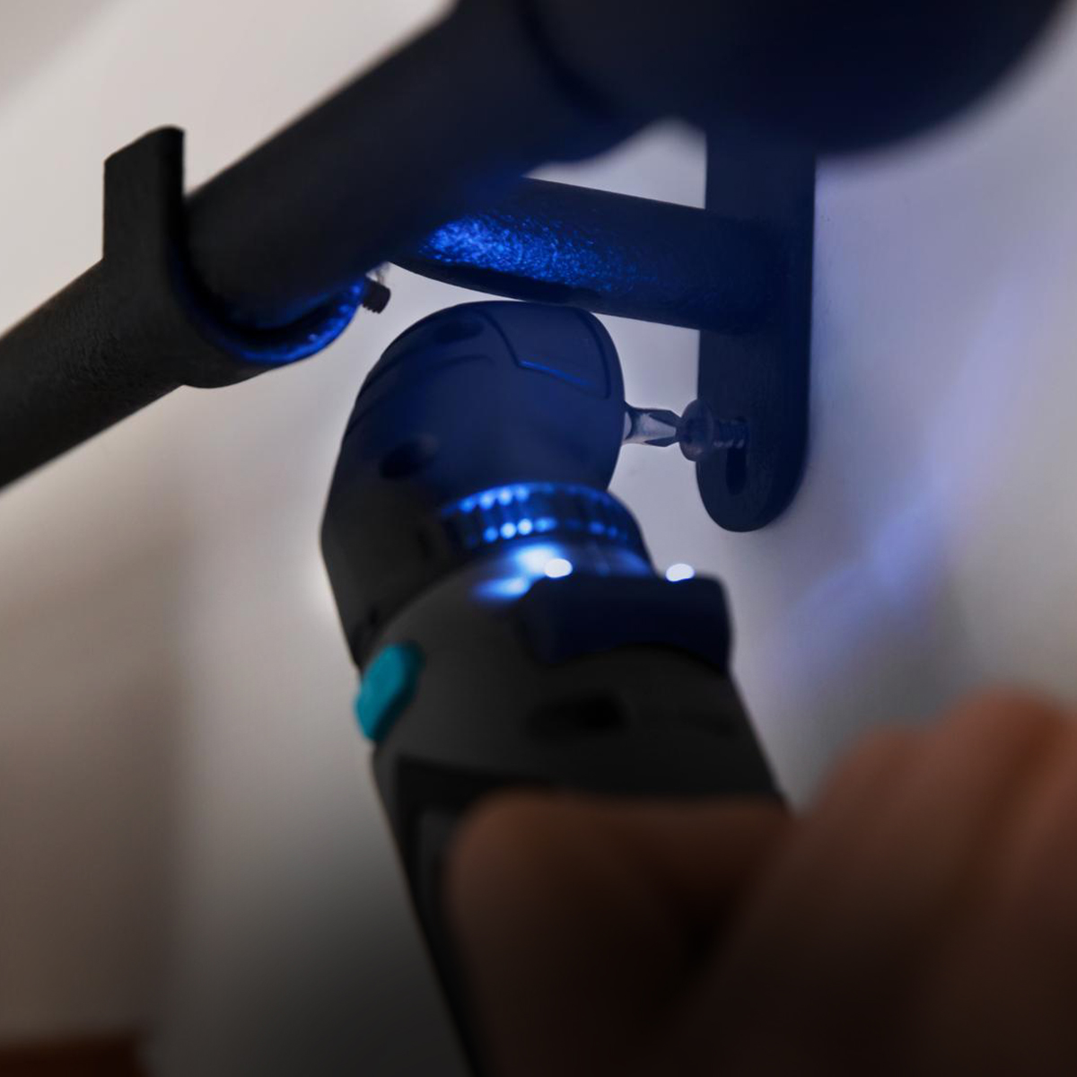 Un cacciavite elettrico con luce viene utilizzato per fissare una staffa per asta per tende nera alla parete.