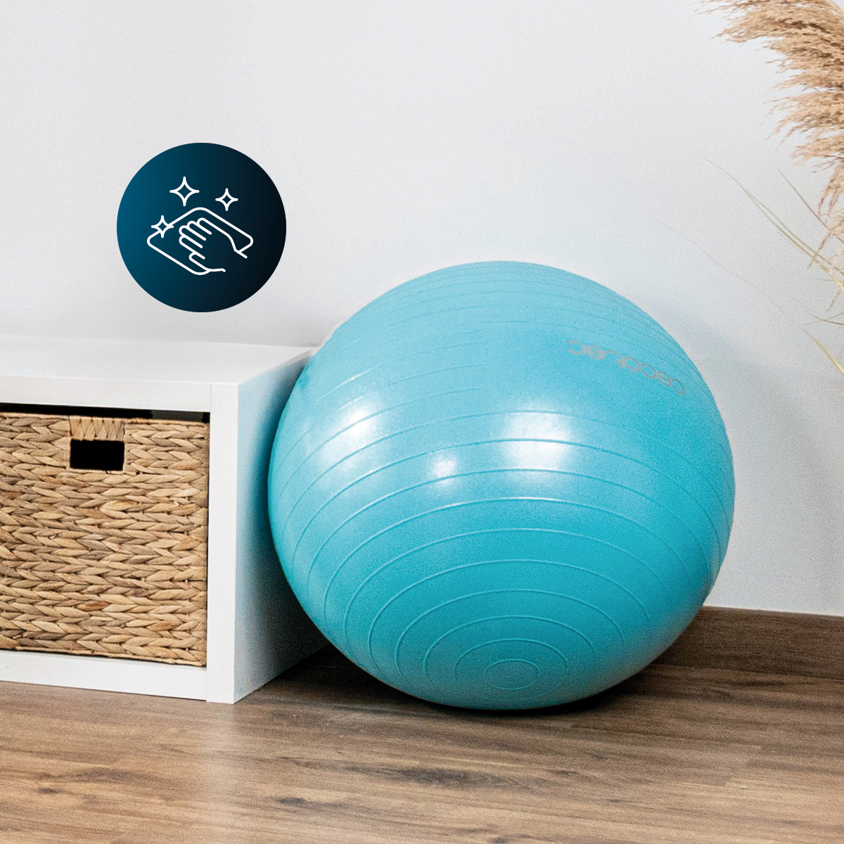Una pelota de ejercicio azul descansa sobre el suelo de madera junto a un mueble blanco.