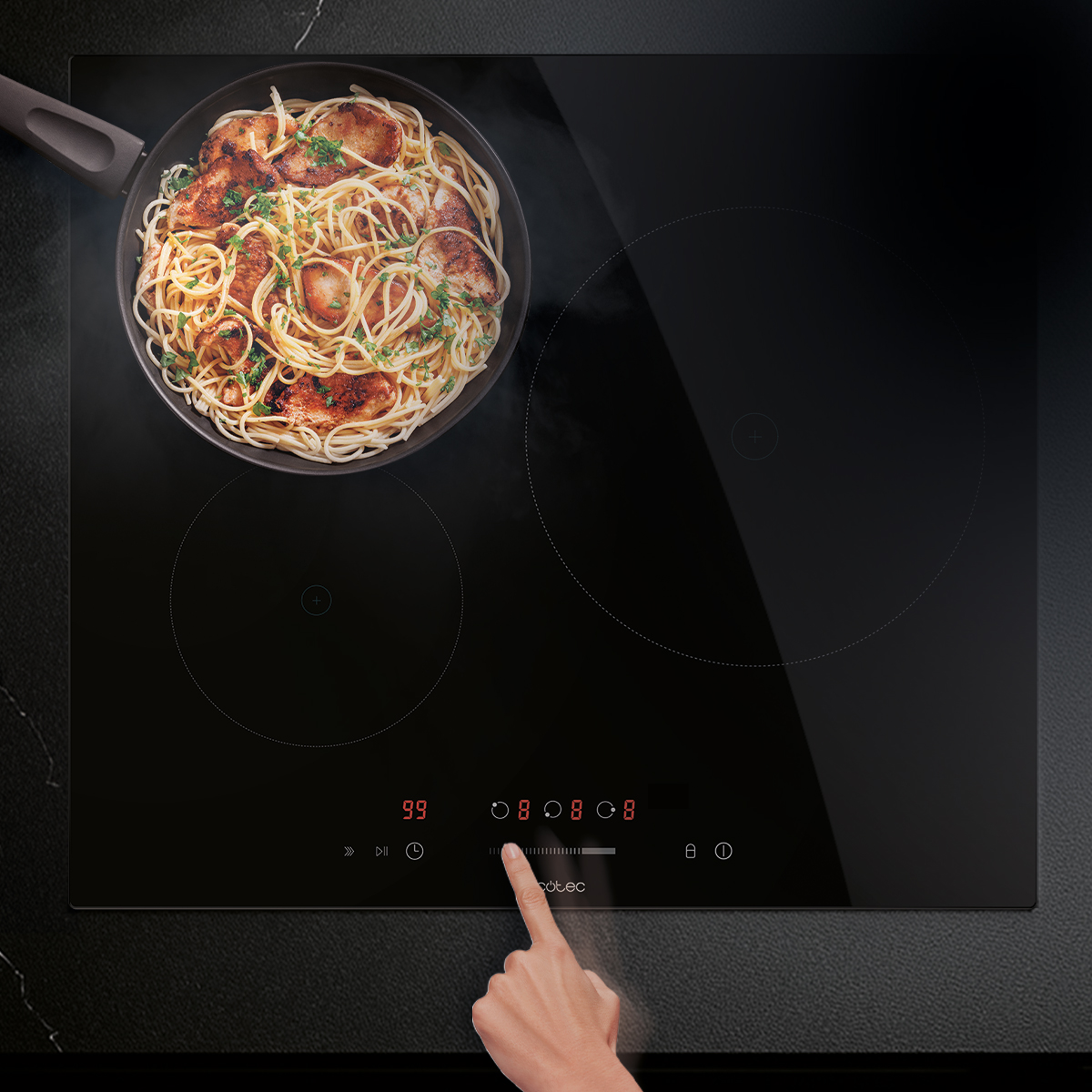 Mano operando placa de inducción negra con sartén llena de pasta y carne.