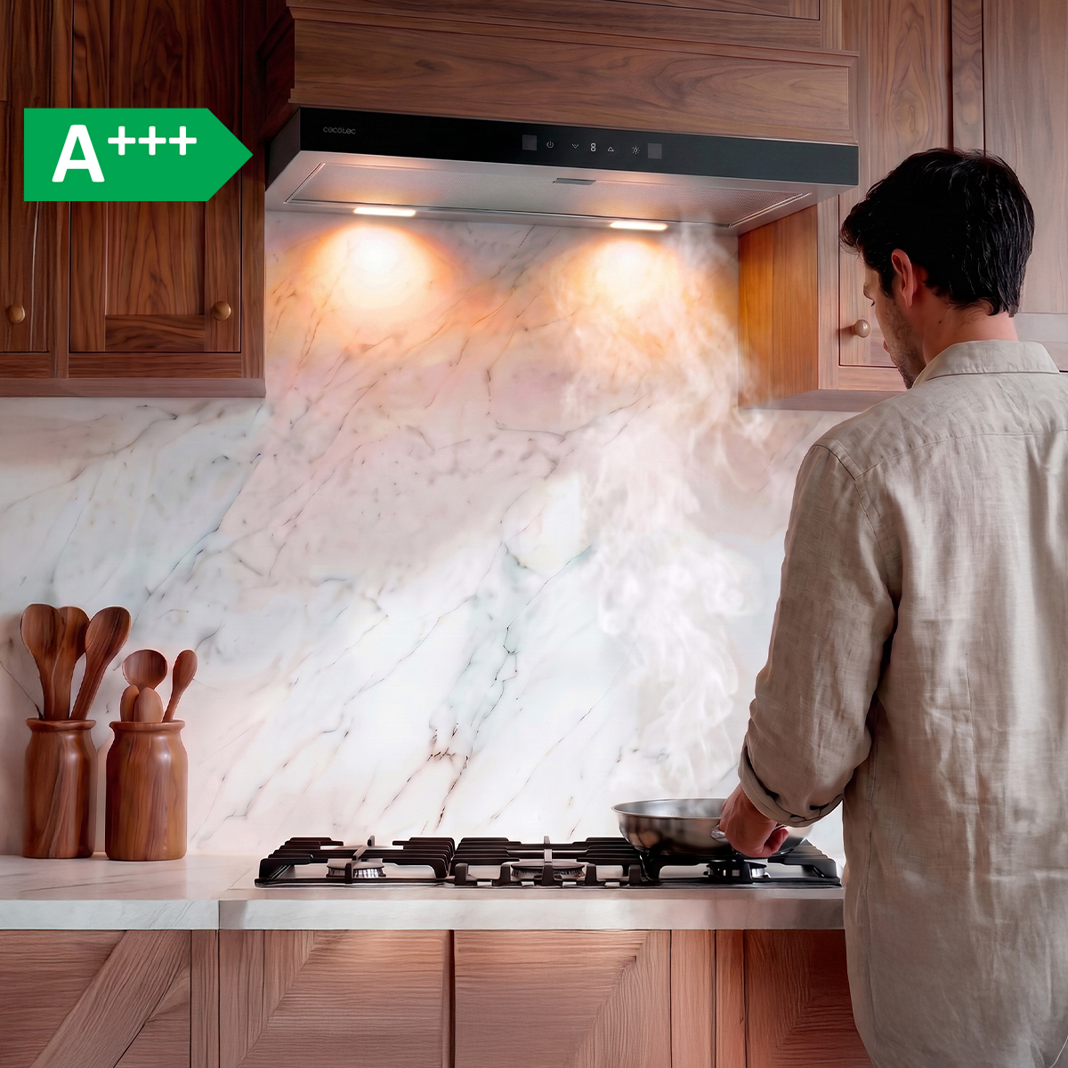 Un hombre cocina en una estufa bajo una campana extractora en una cocina moderna de madera, con salpicadero de mármol y vapor.
