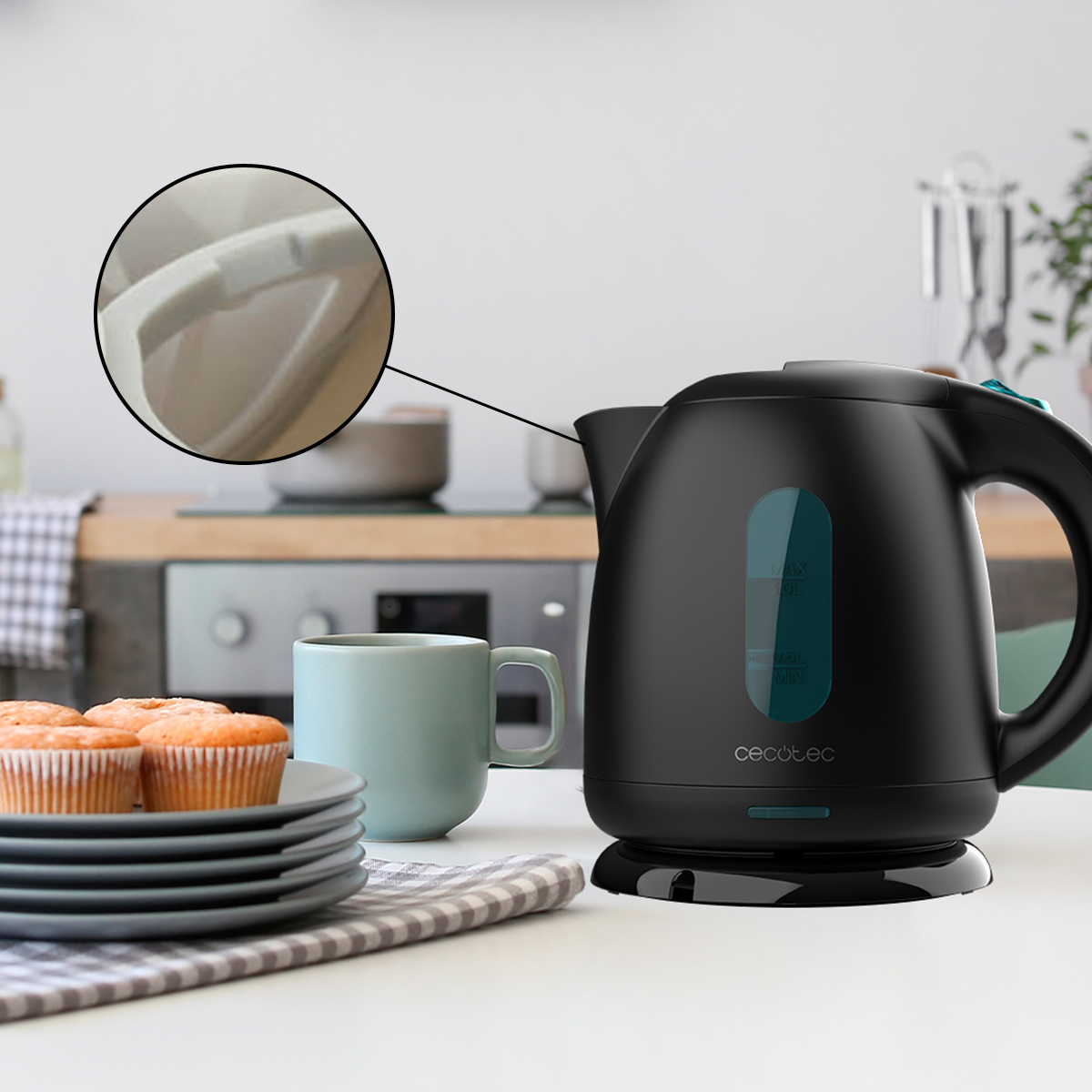 Un hervidor eléctrico negro sobre una encimera junto a magdalenas y una taza. Un recuadro muestra el pico.