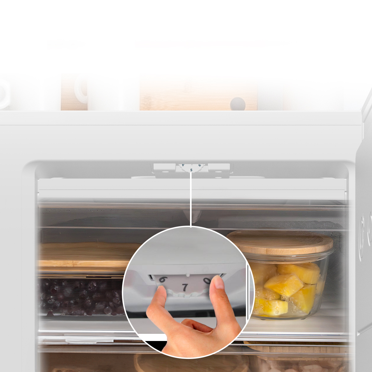Una mano ajusta el dial de control de temperatura dentro de un refrigerador blanco.