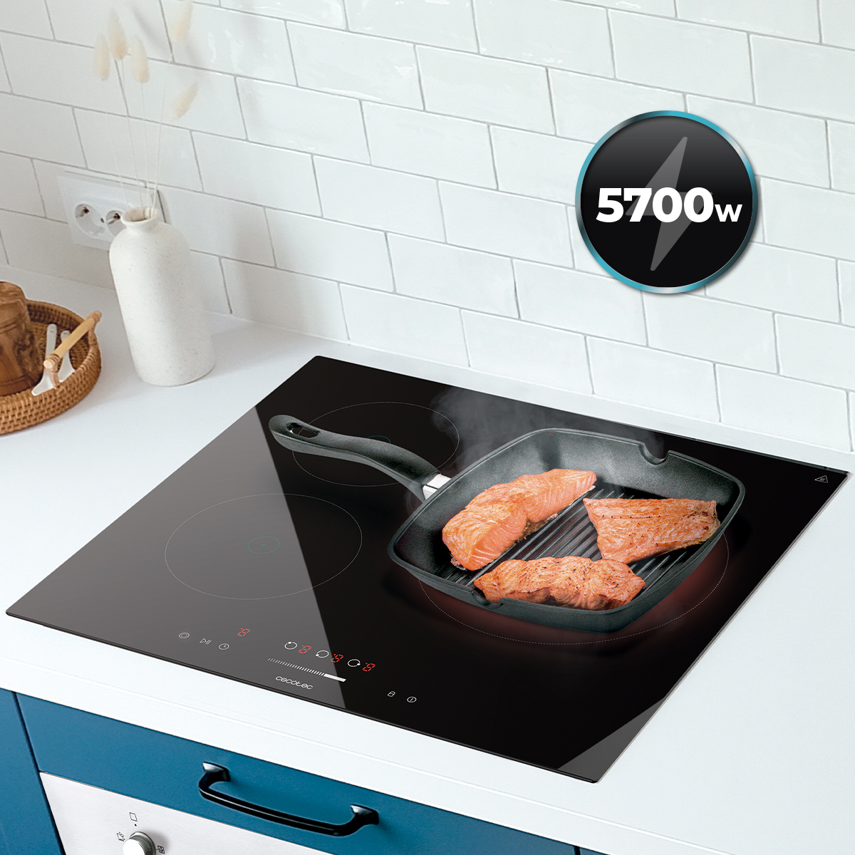 Filetes de salmón cocinándose en una sartén grill sobre una placa de inducción negra en una cocina blanca.