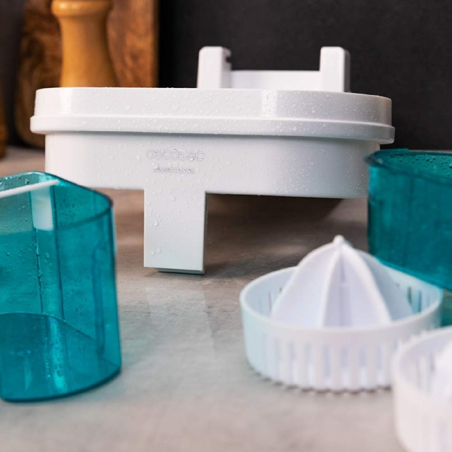 Un spremiagrumi bianco con contenitori blu e gocce d'acqua su un bancone della cucina.