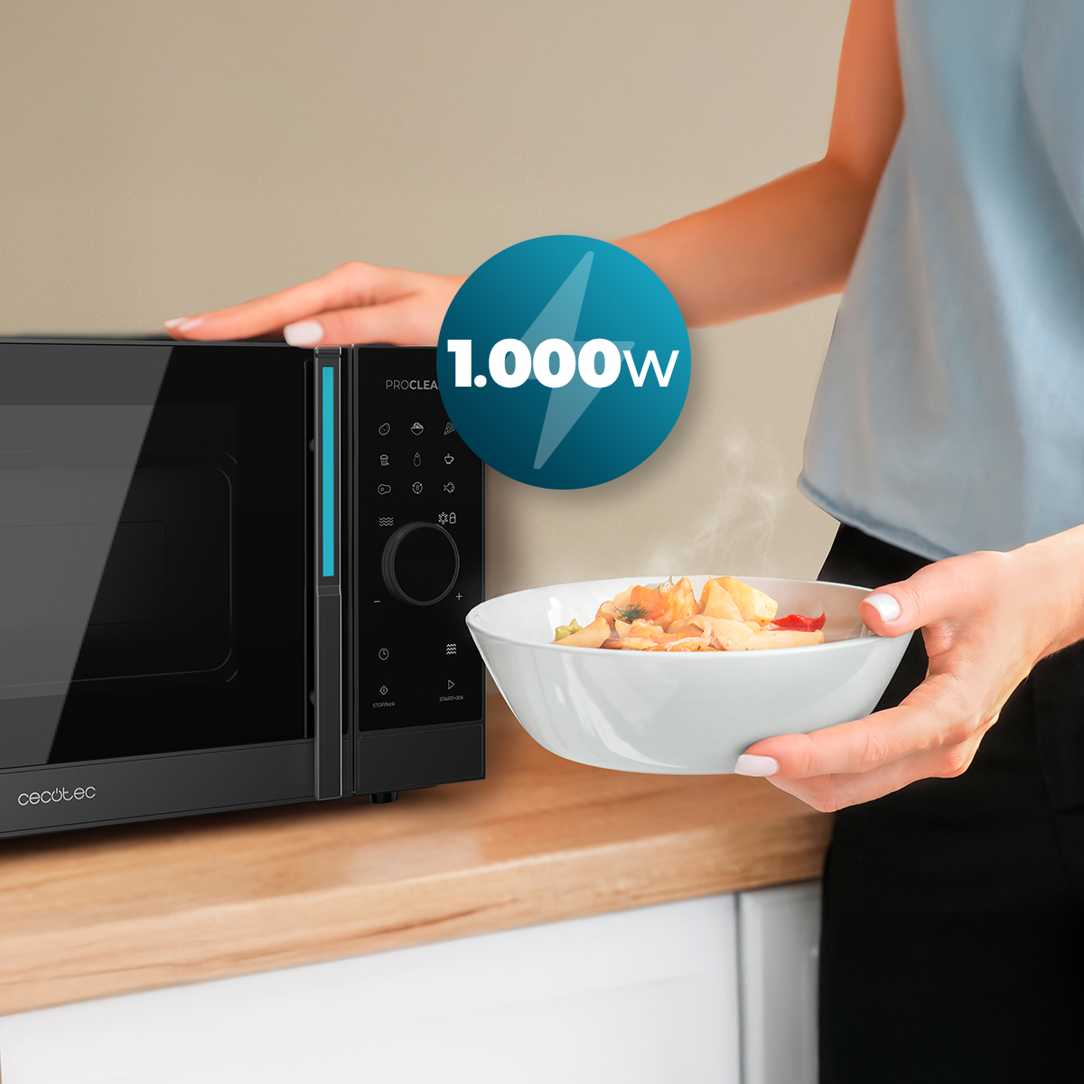 Una mujer sostiene un bol de comida junto a un microondas negro de 1000W en una encimera.