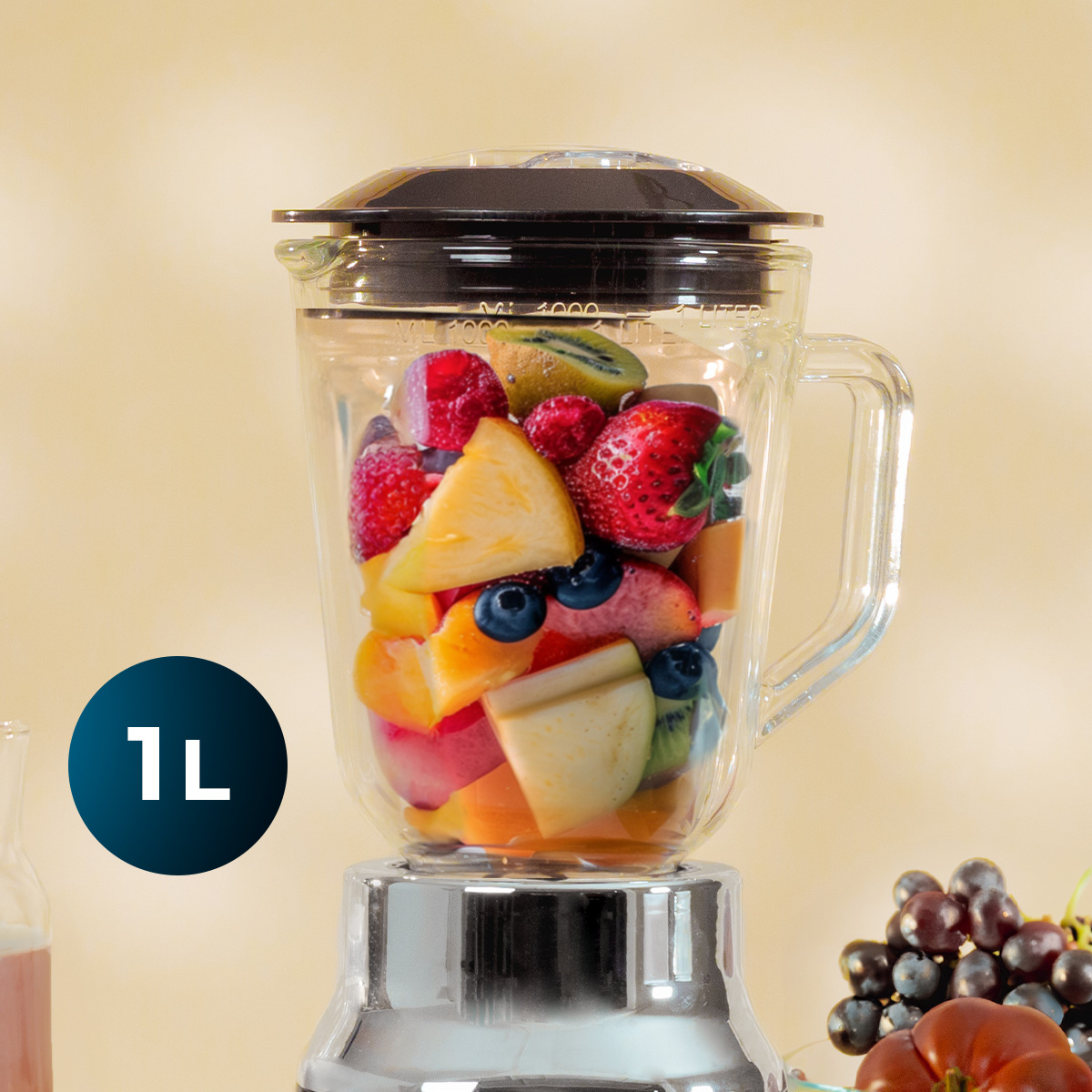 Una licuadora de vidrio llena de frutas frescas como fresas, kiwi y piña, con una etiqueta azul de 1L.
