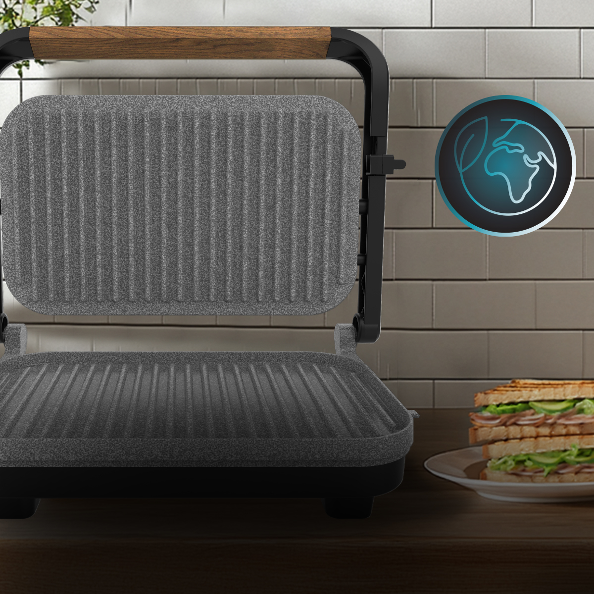 Una parrilla eléctrica de contacto con placas grises y mango de madera está en una mesa de cocina junto a un sándwich.